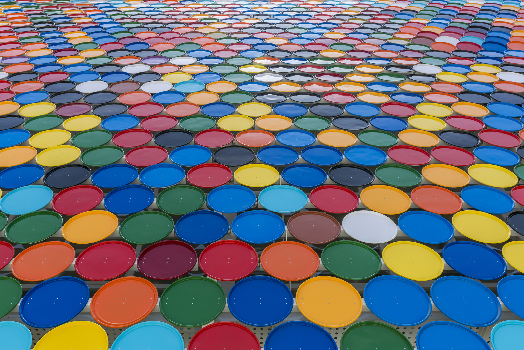 Roof view of multicolored circular glass panels arranged in overlapping rows creating patterned canopy