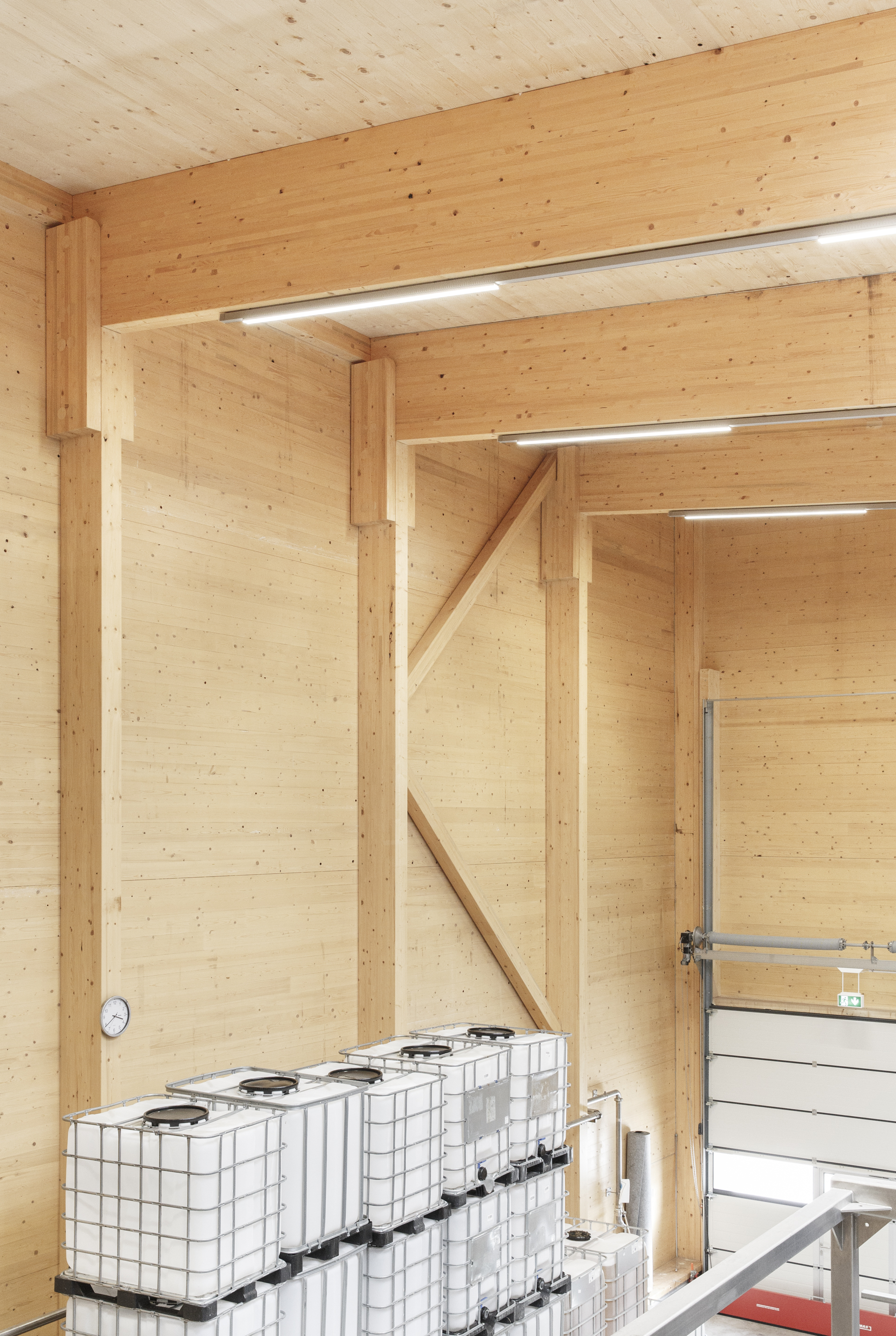 Corner detail of timber post and beam frame with white storage containers at floor level