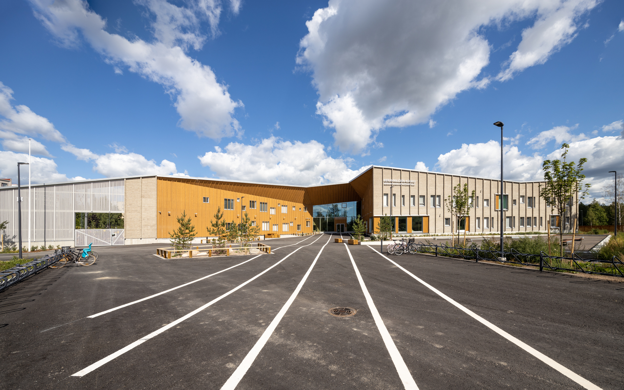 Front elevation showing the curved timber section linking two volumes under passing summer clouds