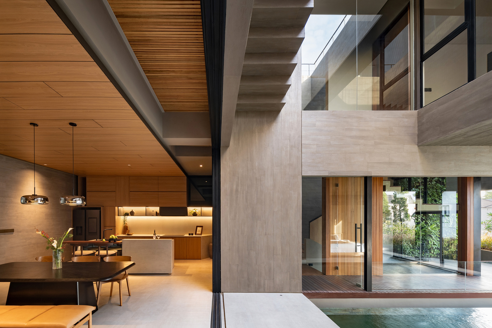 Open-plan kitchen and dining area with timber ceiling, pendant lights overlooking the courtyard pool