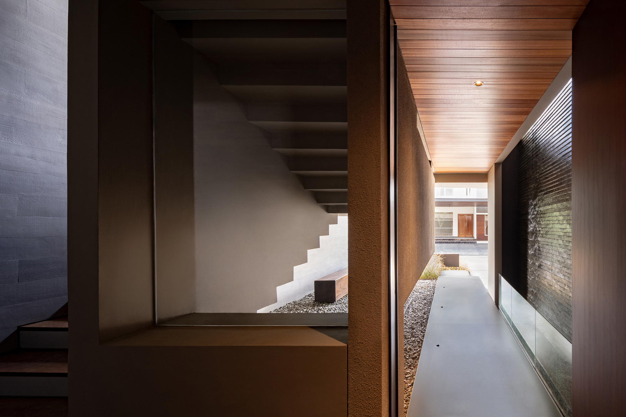 Interior corridor with timber ceiling panels and glimpse of staircase beyond a glazed opening