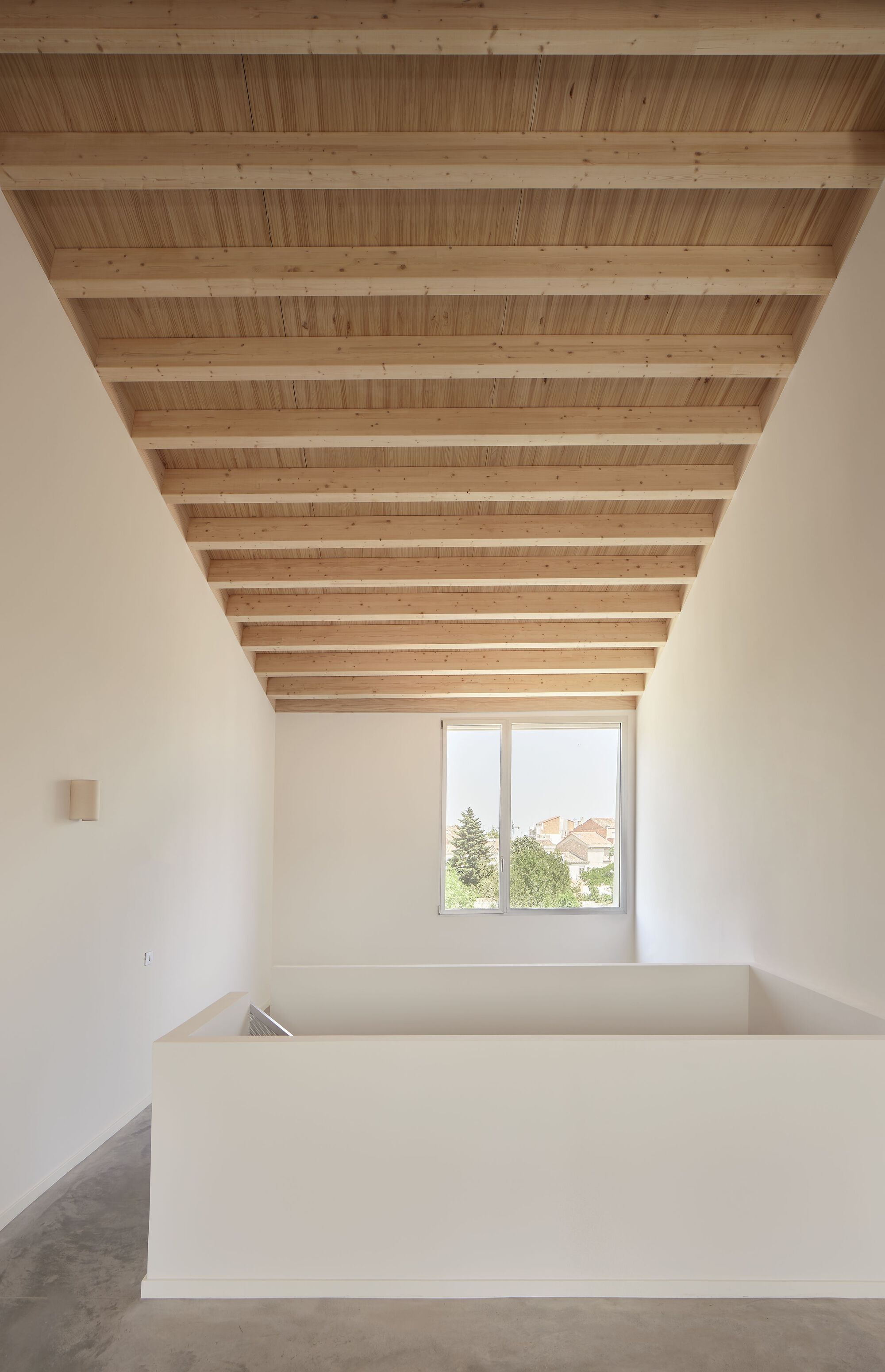 Upper level room with exposed timber joists and decking ceiling, a corner window and white volume below