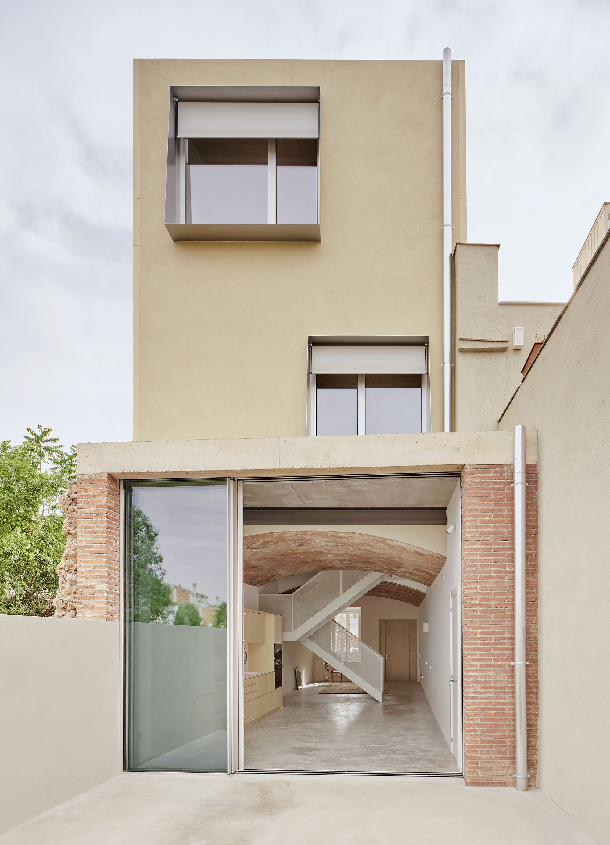 Facade with open glazed ground floor revealing vaulted brick ceiling and timber stair beyond