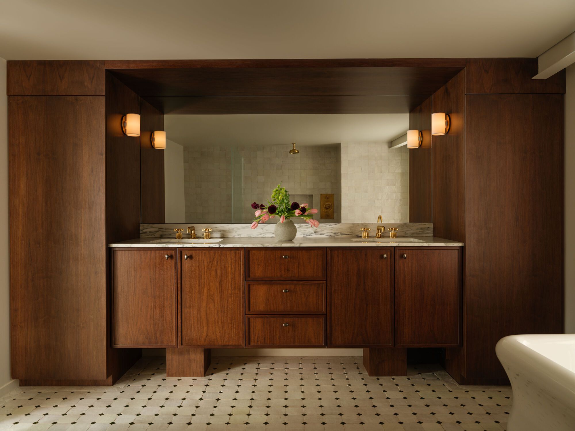 Walnut double vanity with stone countertop, framed mirror, and black and white mosaic floor tile