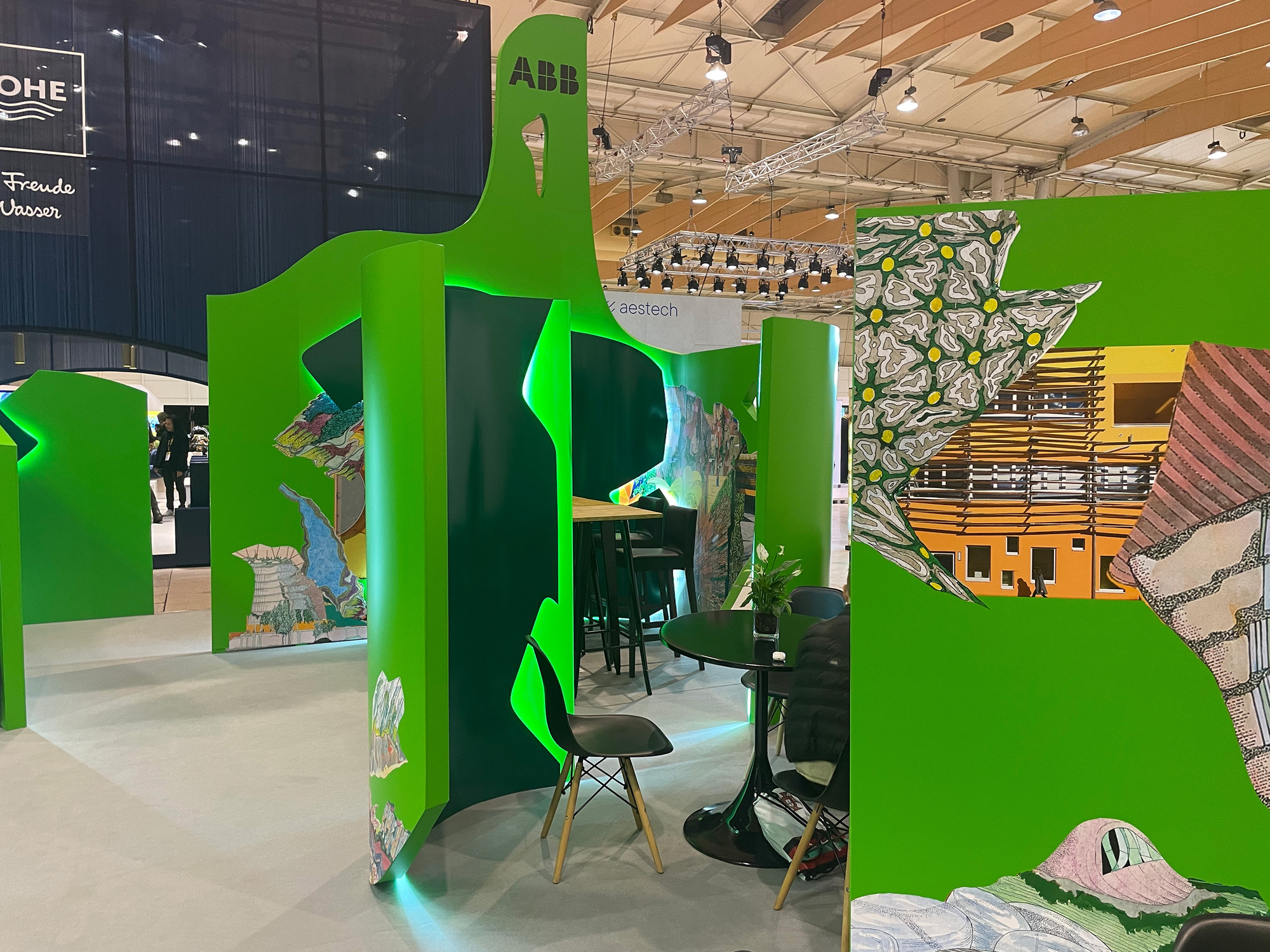 Interior view through curved green partition walls with embedded display panels and seating area