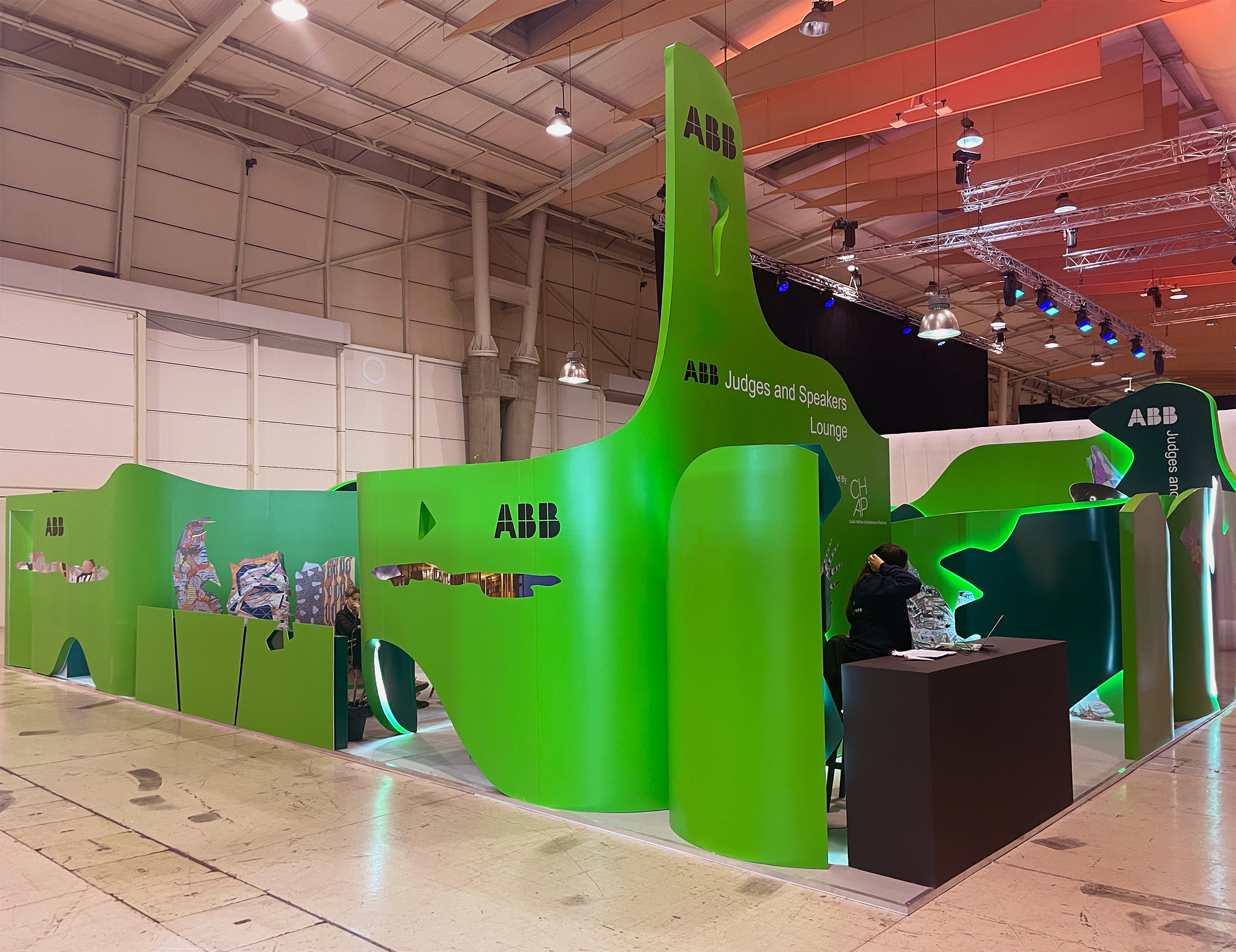 Long view of continuous green curved wall system with reception desk and visitor interaction