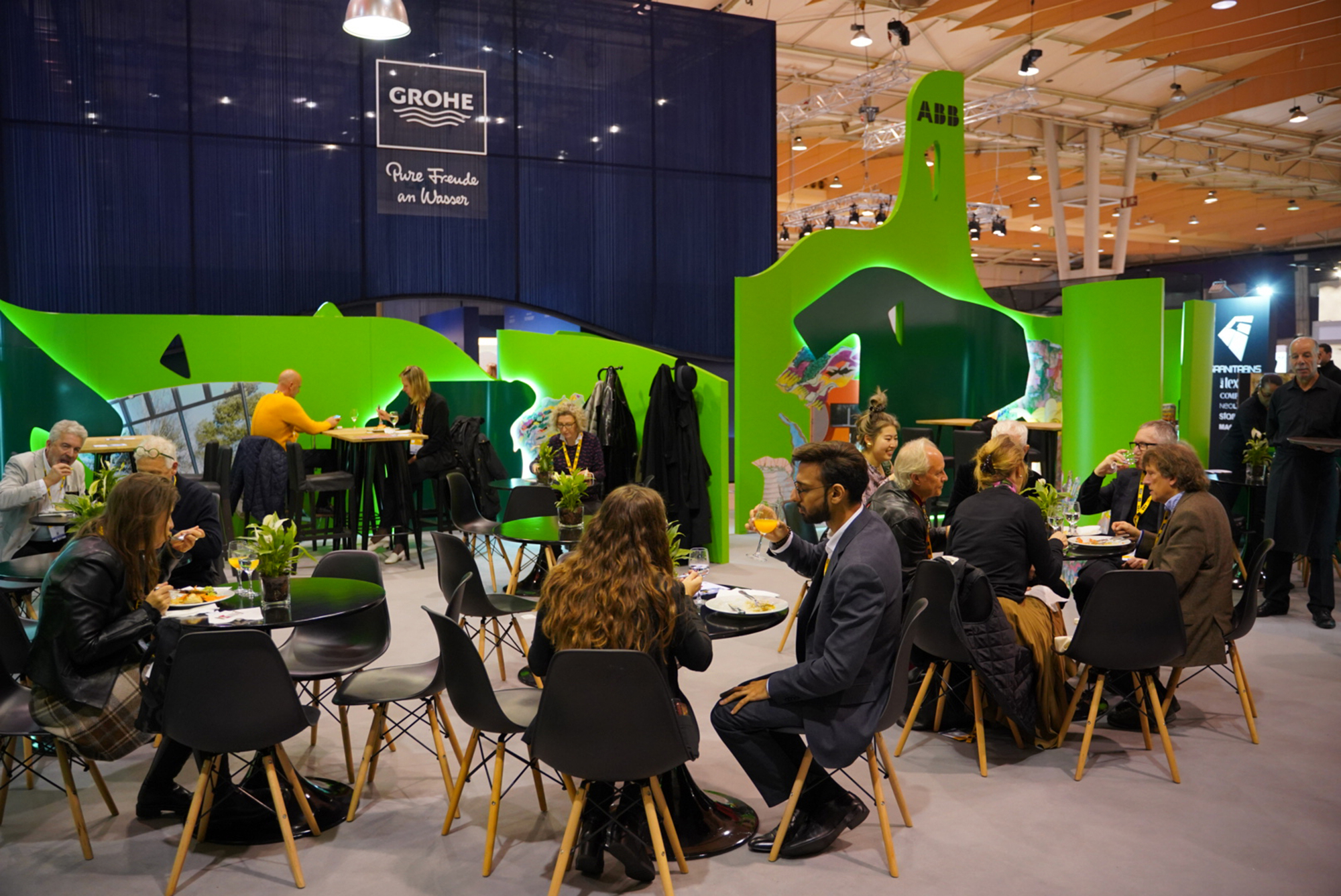 Seating area with round tables and chairs inside a lounge space defined by bright green curving walls