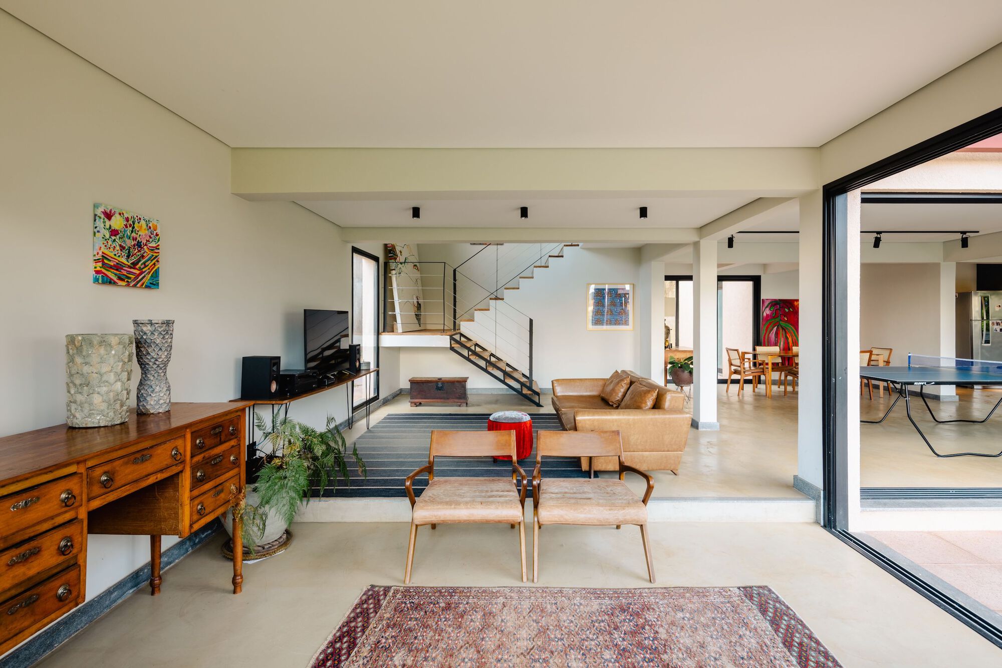 Open-plan living area with concrete floors and exposed steel staircase visible through doorway