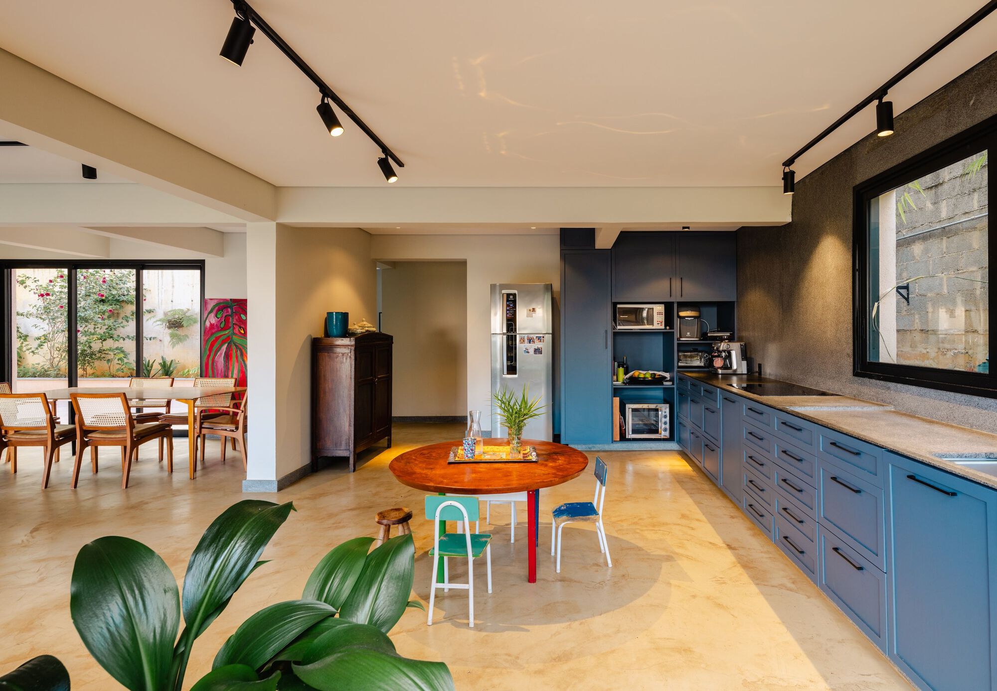 Open-plan kitchen and dining area with dark cabinetry and track lighting under a vaulted ceiling