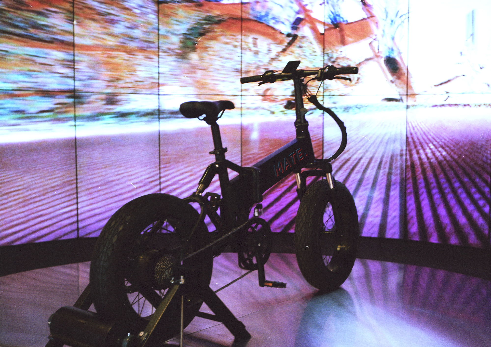 Silhouetted bike on a stand against a multiscreen video wall projection