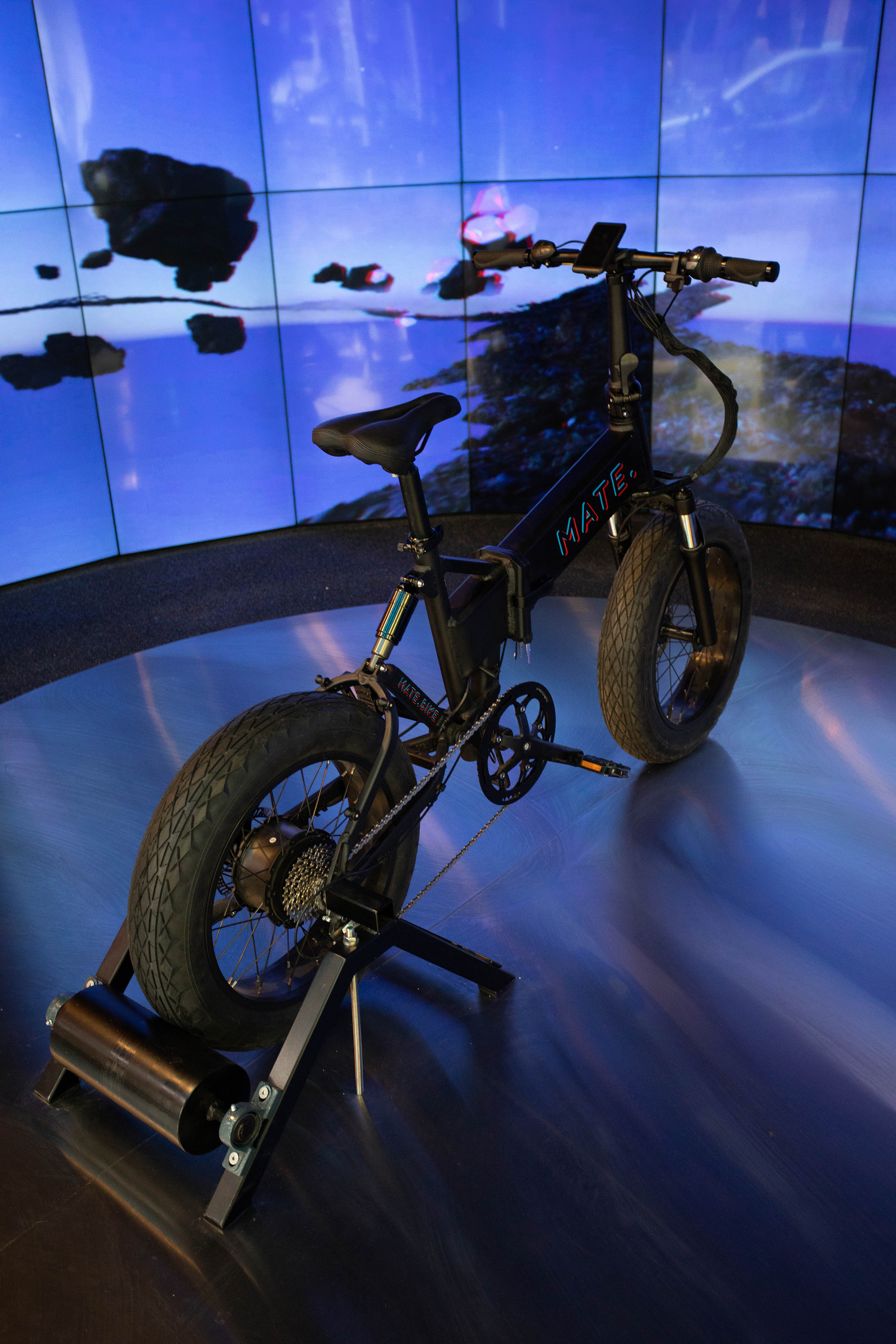 Single bike mounted on a trainer before a curved blue video screen display