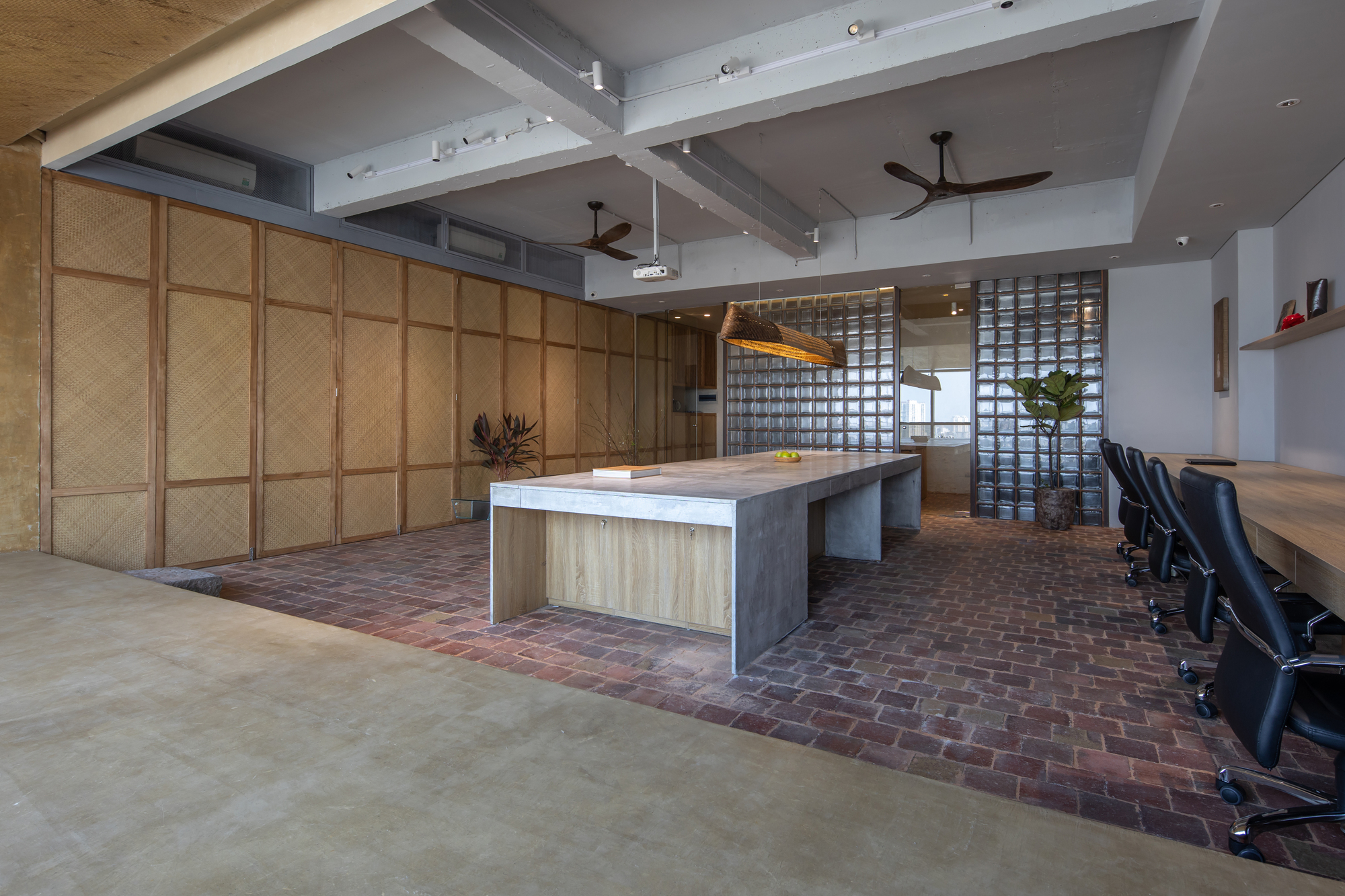 Office interior with folding bamboo screens, exposed concrete beams, and glass block divider wall