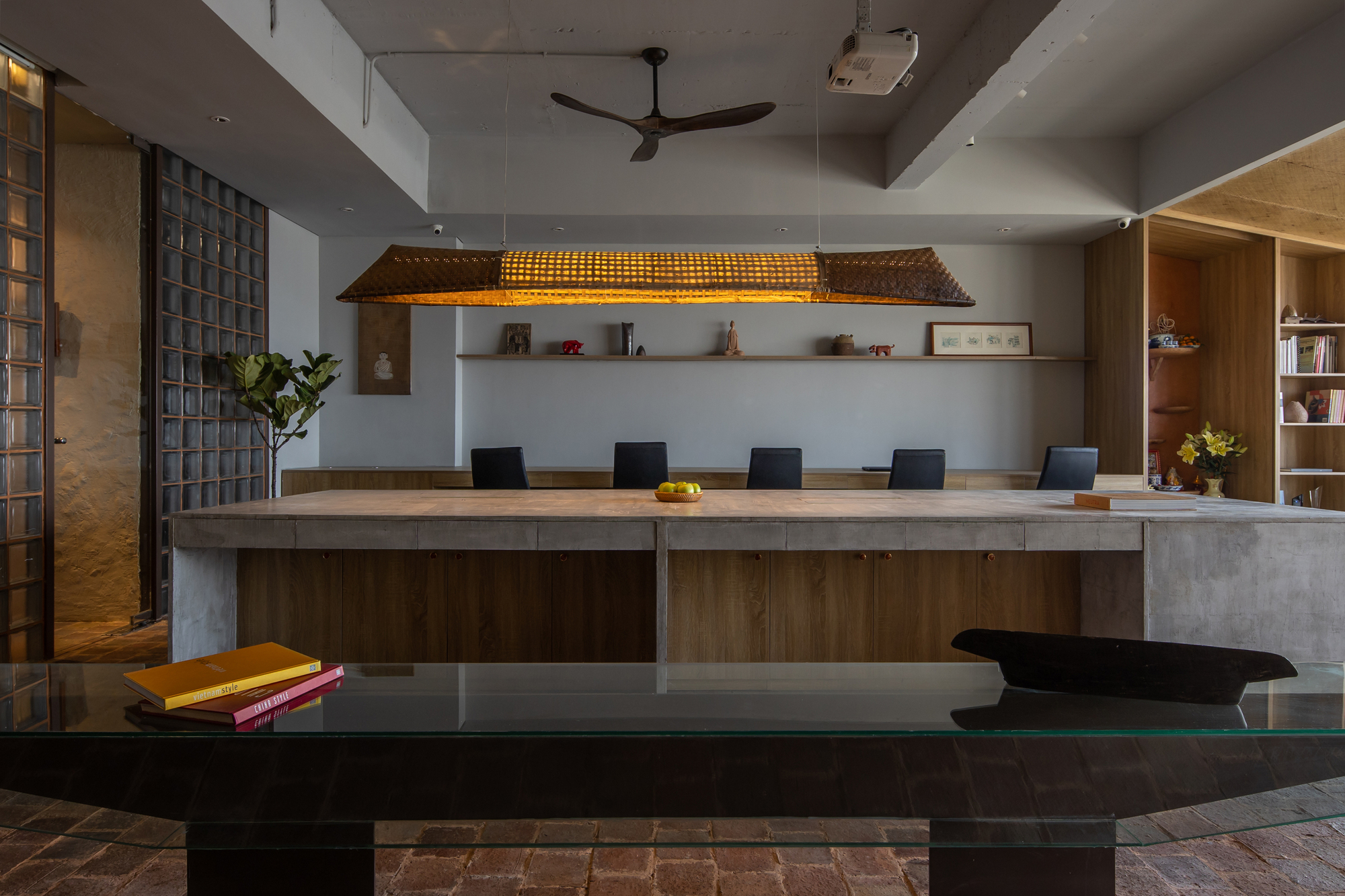 Dining and workspace with timber table, woven pendant light and reclaimed brick flooring beneath a stepped ceiling