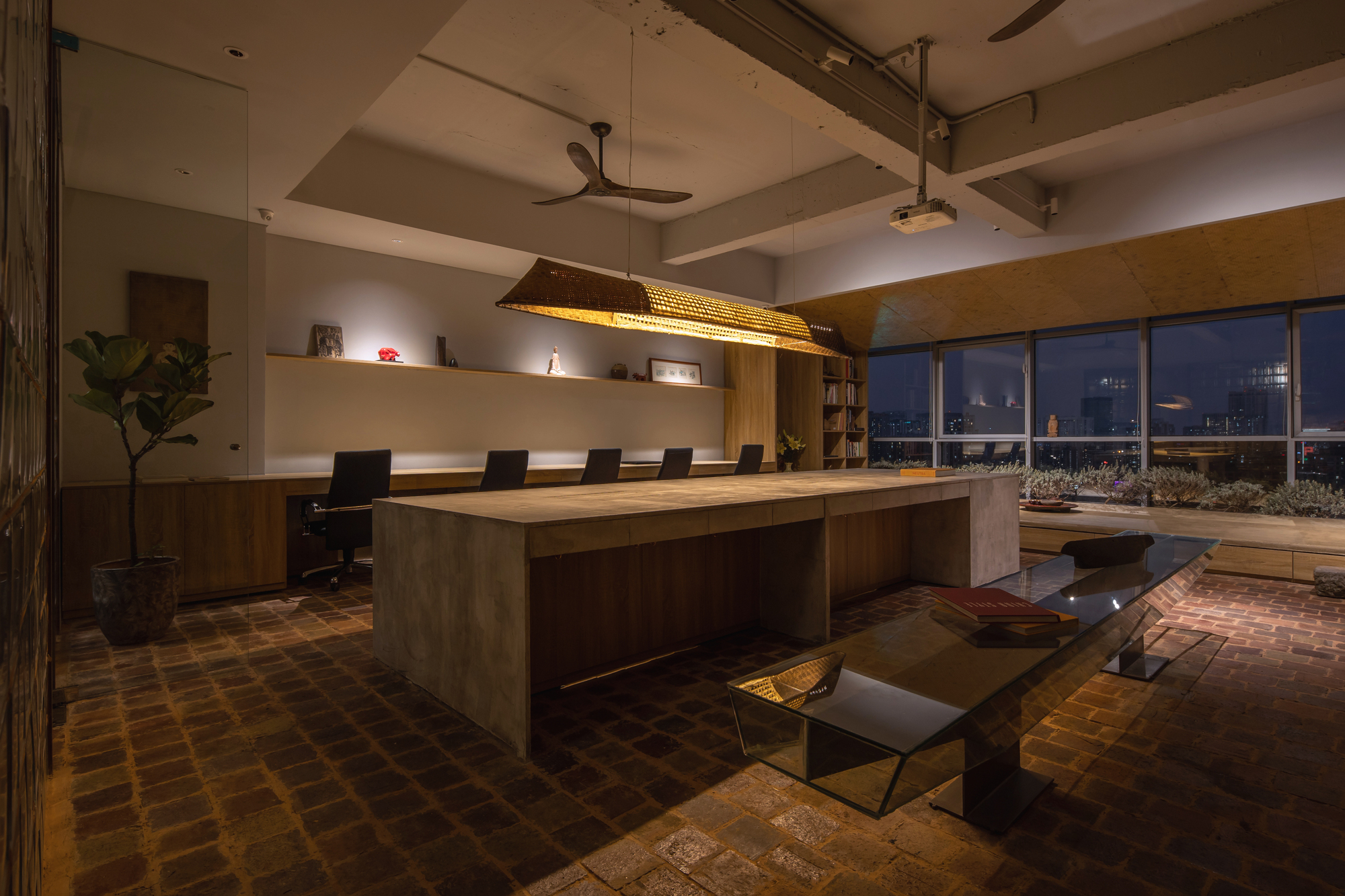 Conference room with long timber table and woven pendant light beneath exposed concrete beams at evening