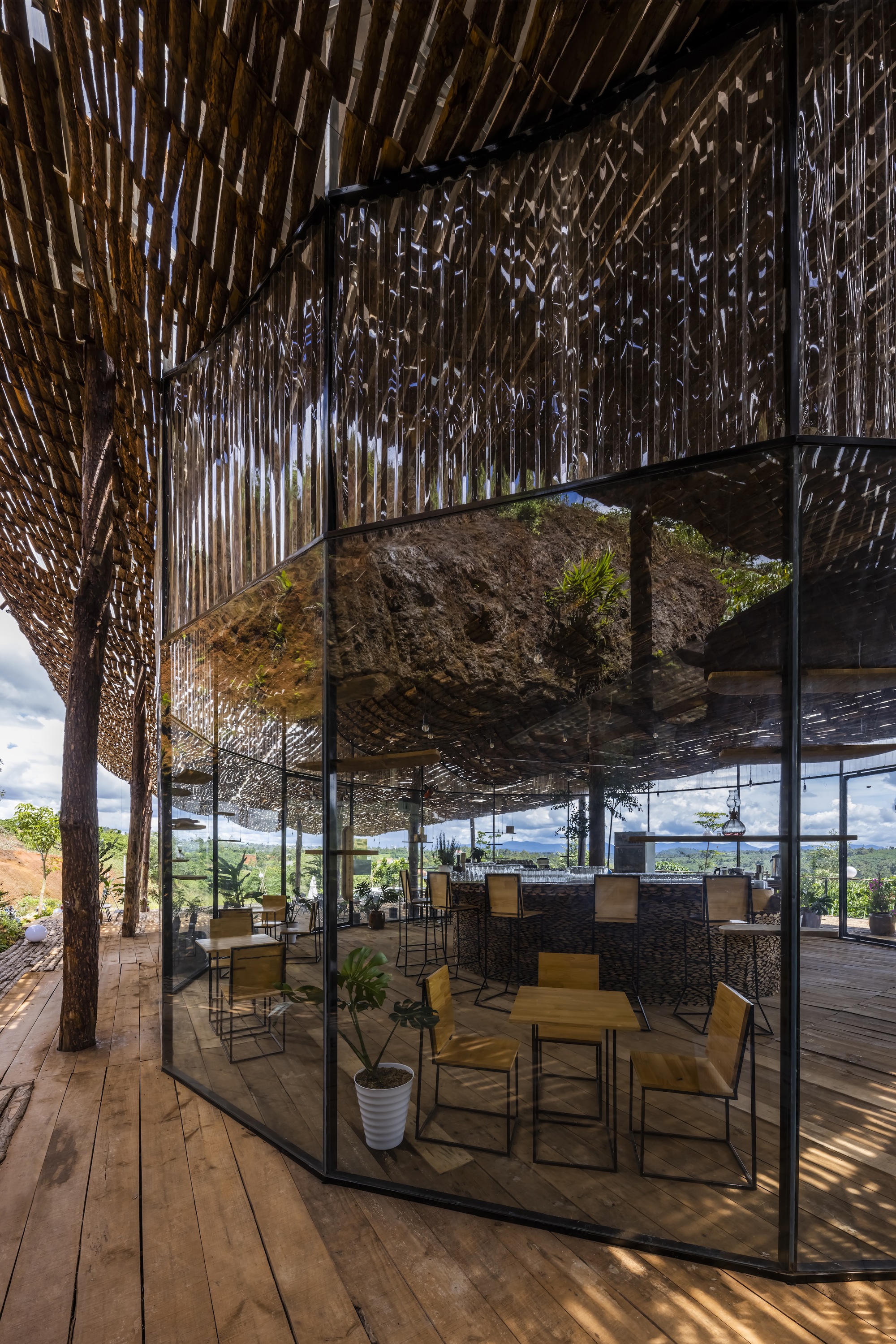 Glass-enclosed lounge area with a suspended rock feature beneath the timber lattice roof structure