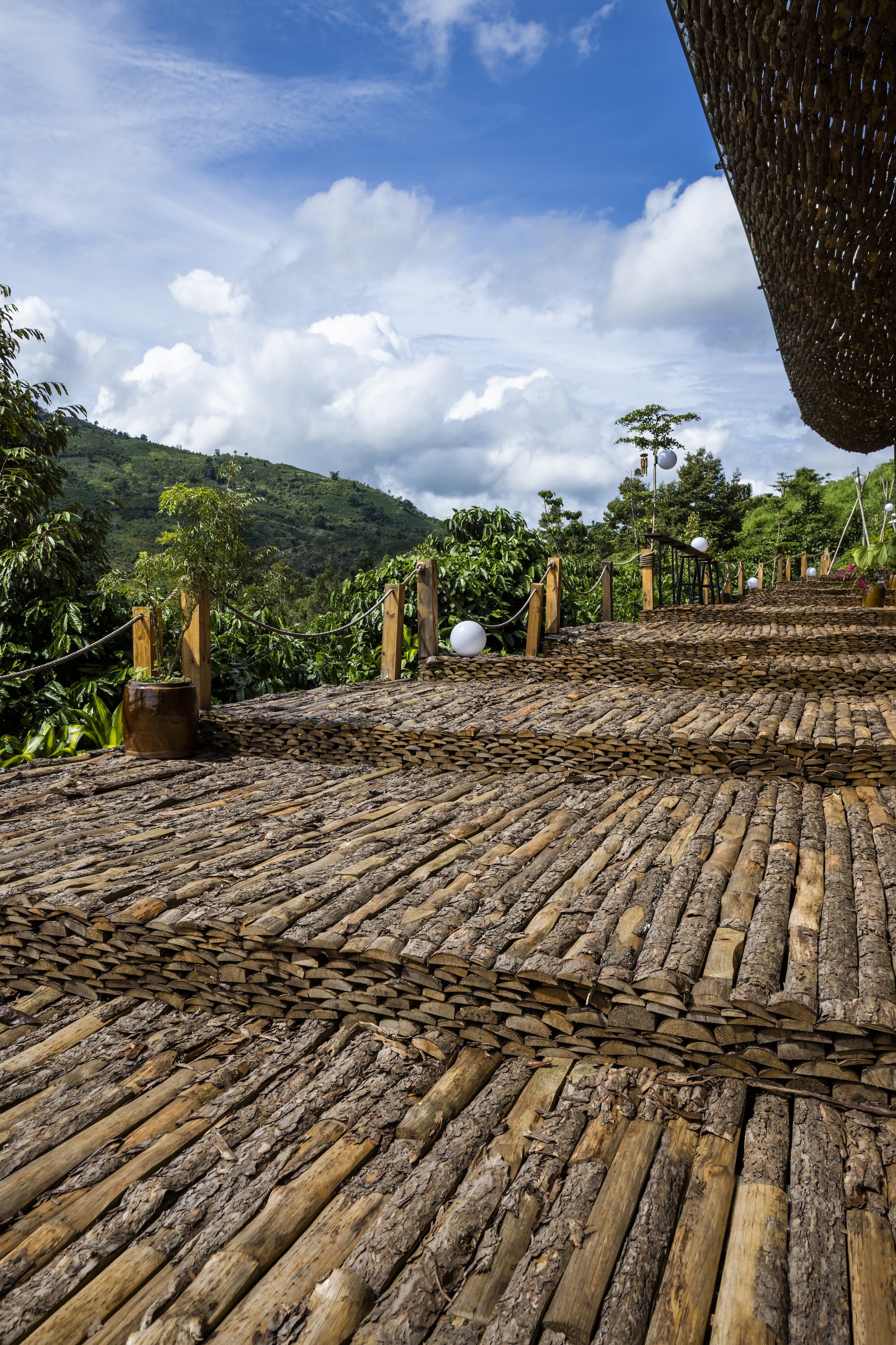 Curved bamboo decking with timber post railing leading toward forested hills