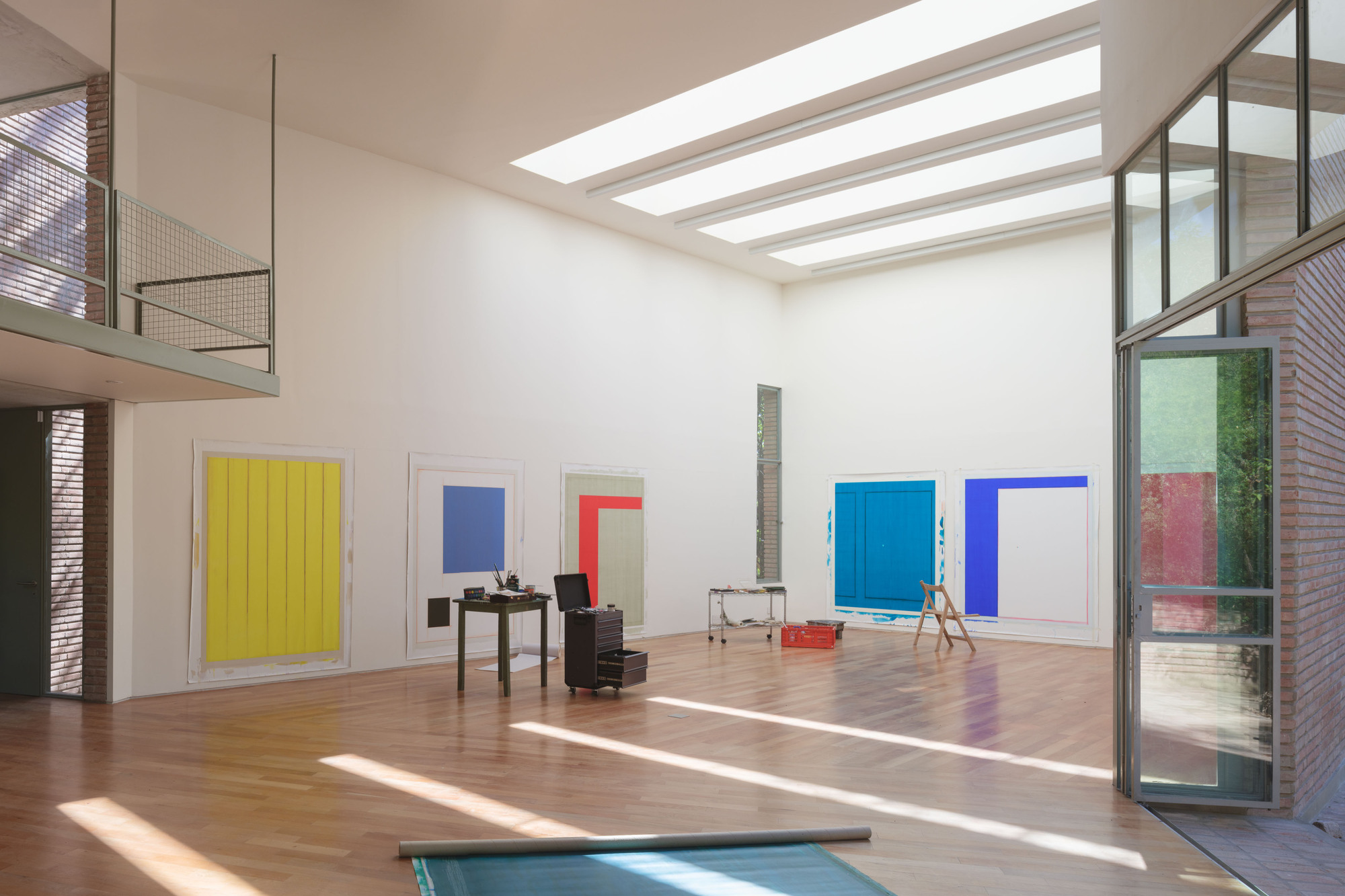 Sunlight streaming through overhead glazing onto timber floor with pivoting steel and glass door panels partly open