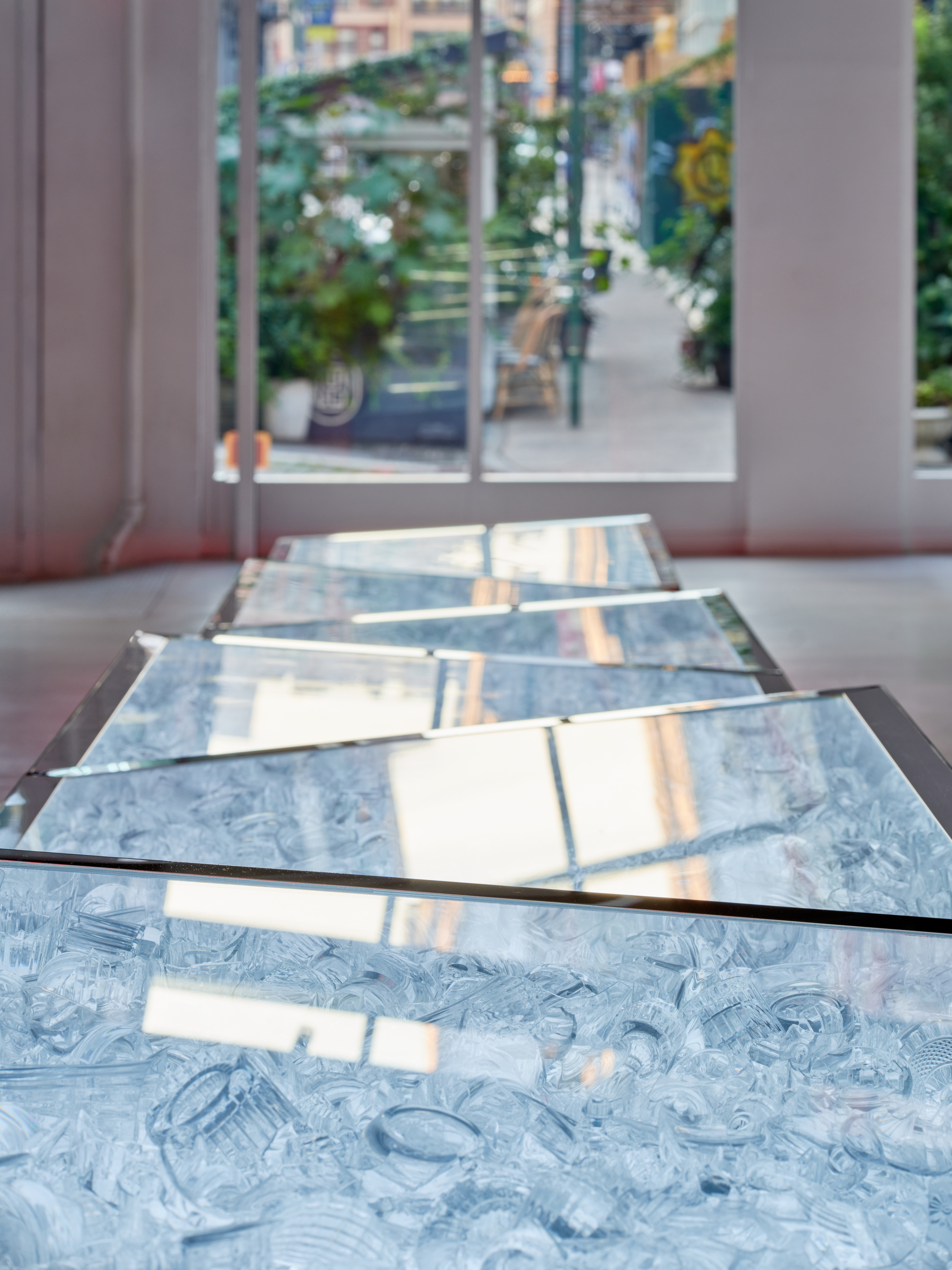 Marbled blue glass floor panels with bronze edging reflecting window light and street view