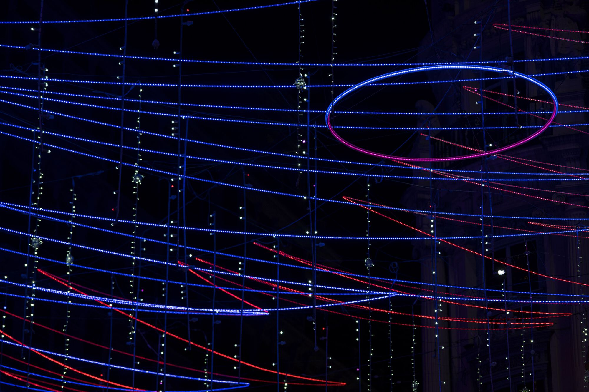 Tilted view of the glowing elliptical ring intersecting layers of horizontal blue and red LED strands