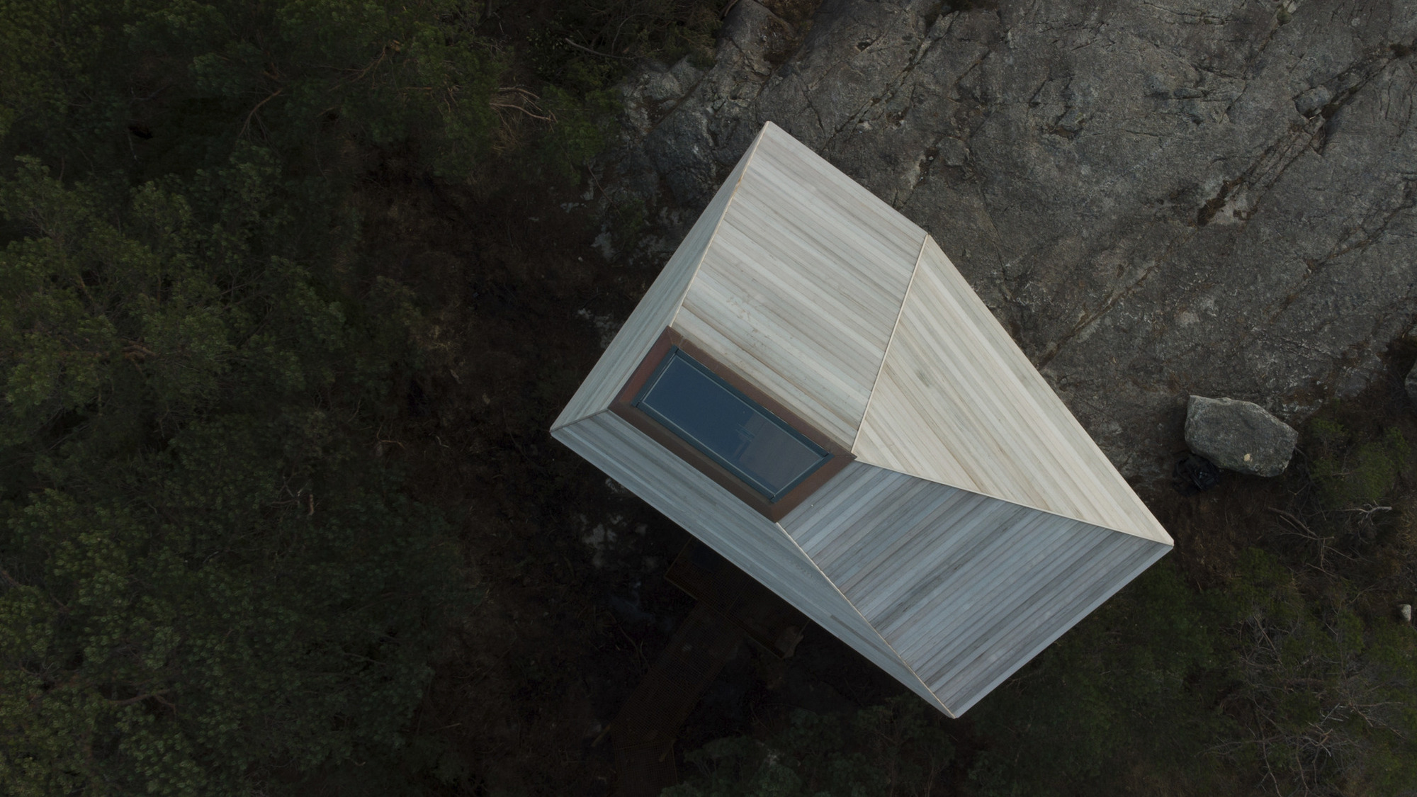 Aerial view of the gabled roof with central skylight perched on rocky outcrop
