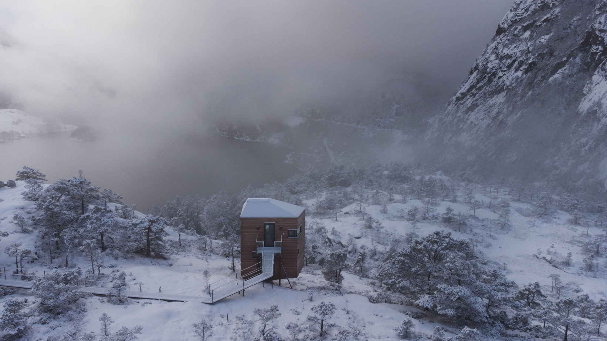 Aerial perspective of the timber structure in heavy snowfall with low cloud over the valley