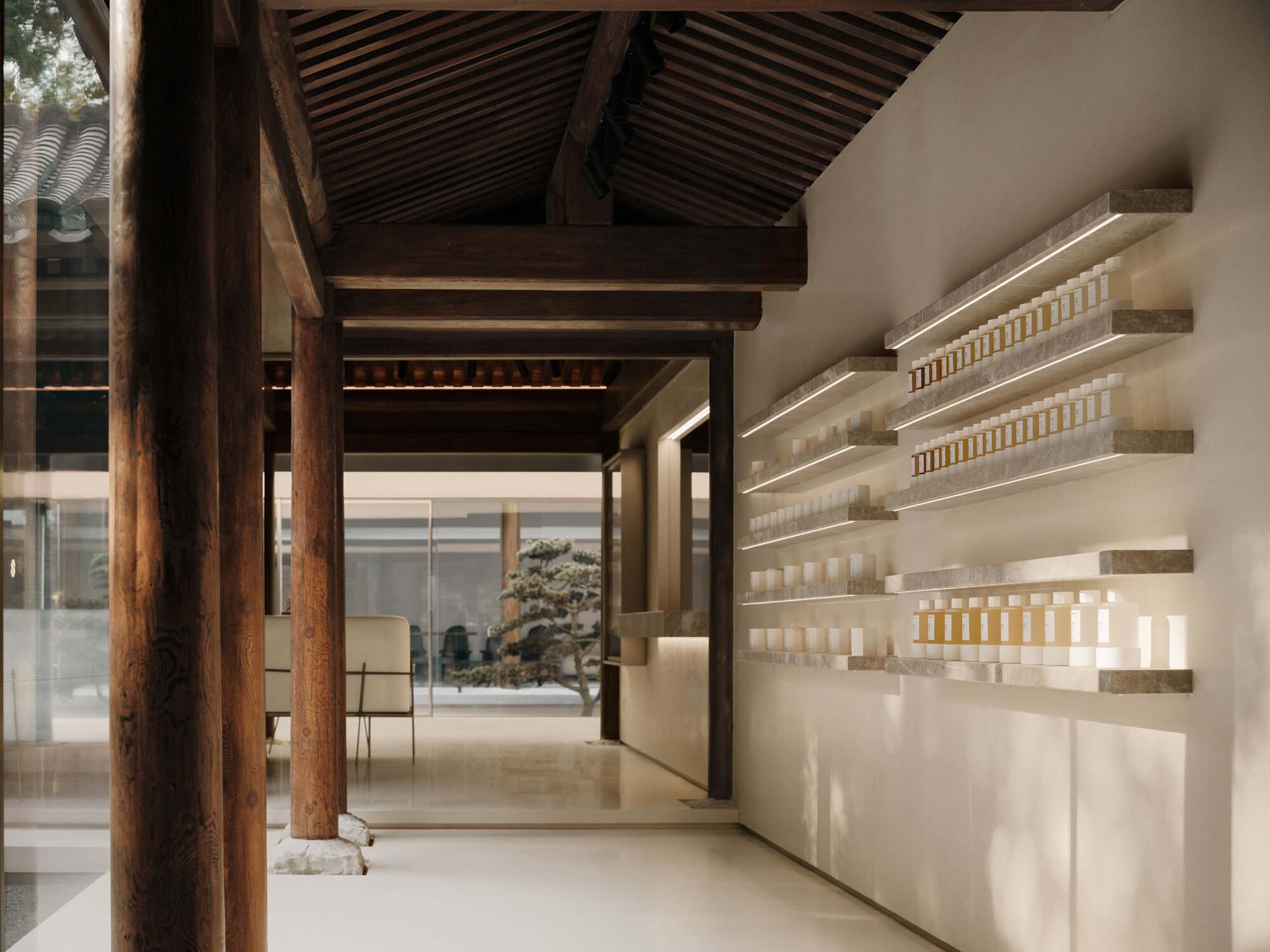 Interior with exposed timber beams and columns alongside illuminated product shelving along a white wall