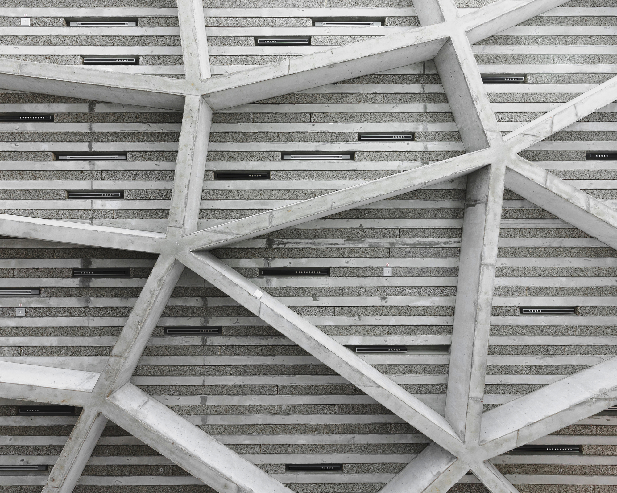 Upward view of textured ceiling with diagonal timber beams and integrated linear lighting