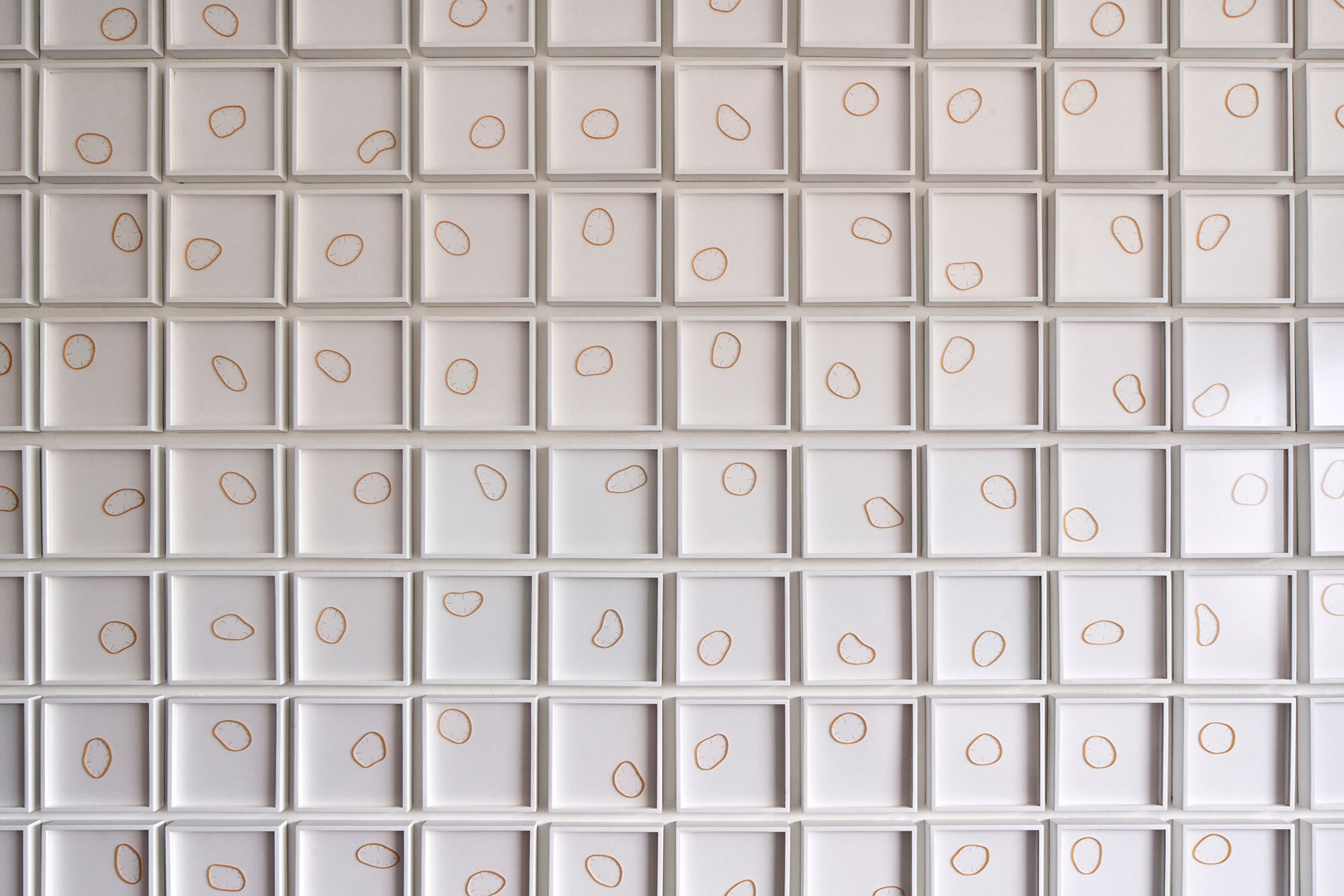White grid wall panel with copper wire loops set into each recessed square cell