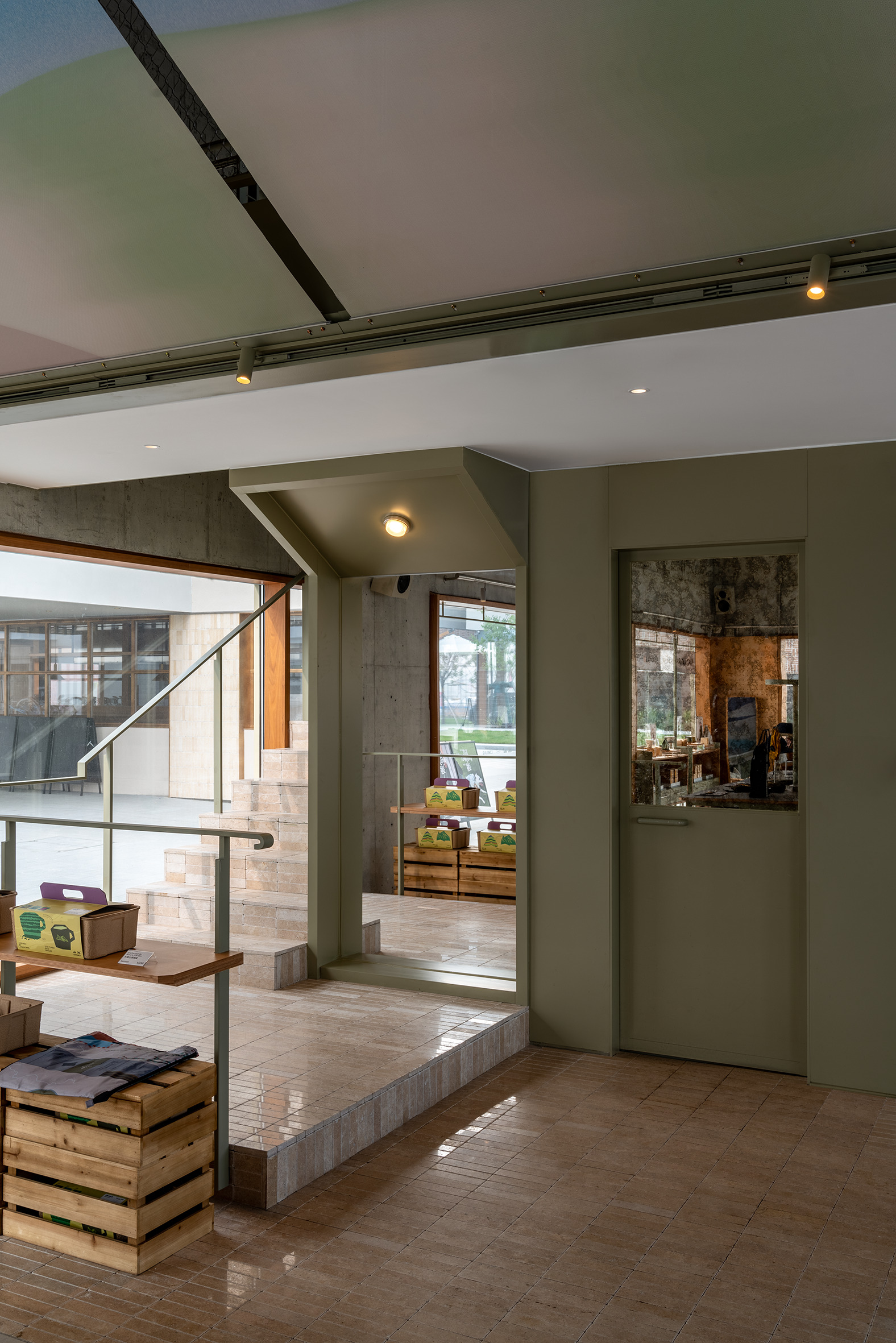 Split-level interior with concrete steps and timber flooring beneath a mezzanine with metal railing