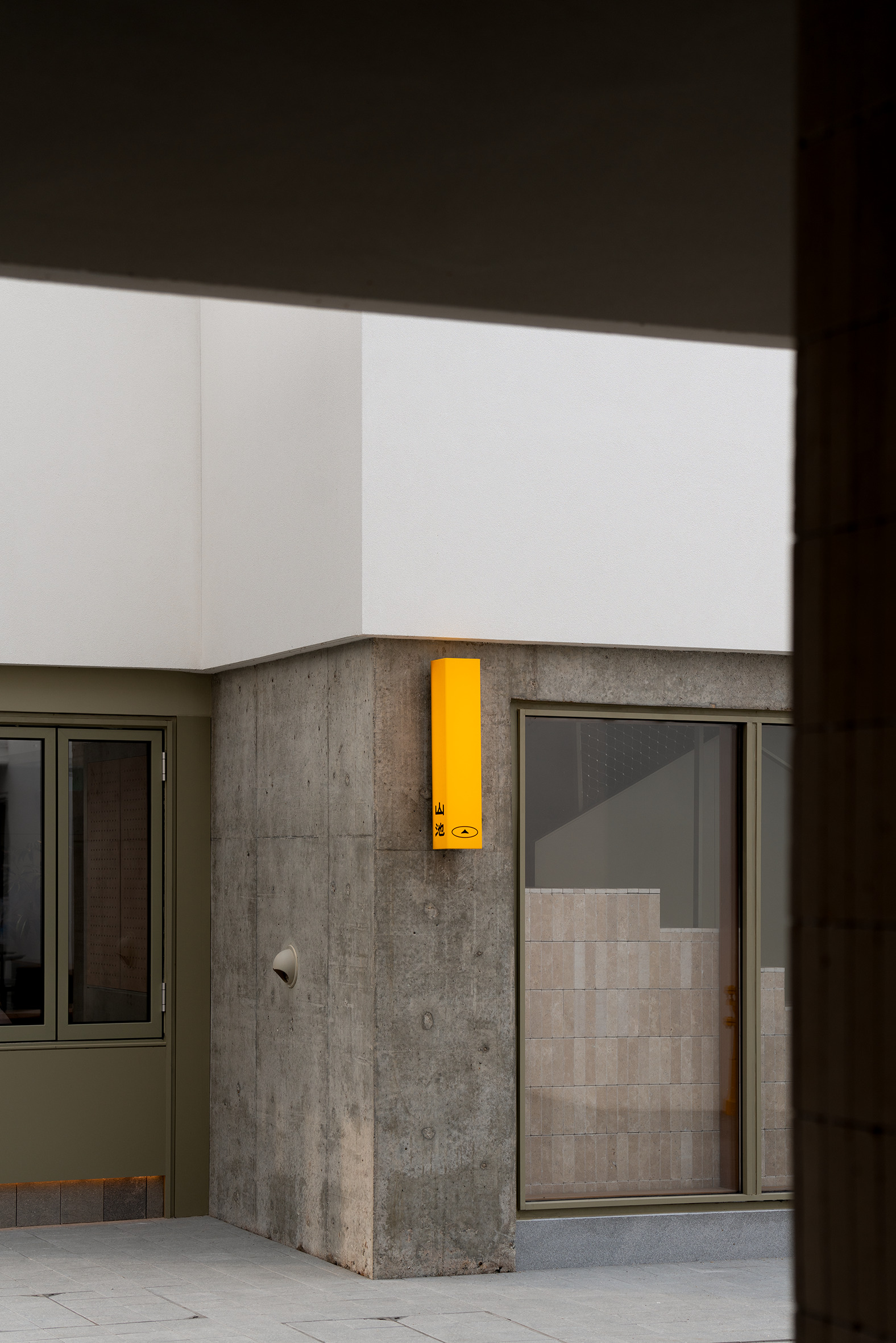 Interior courtyard corner with yellow emergency call box mounted on a cast concrete column at dusk