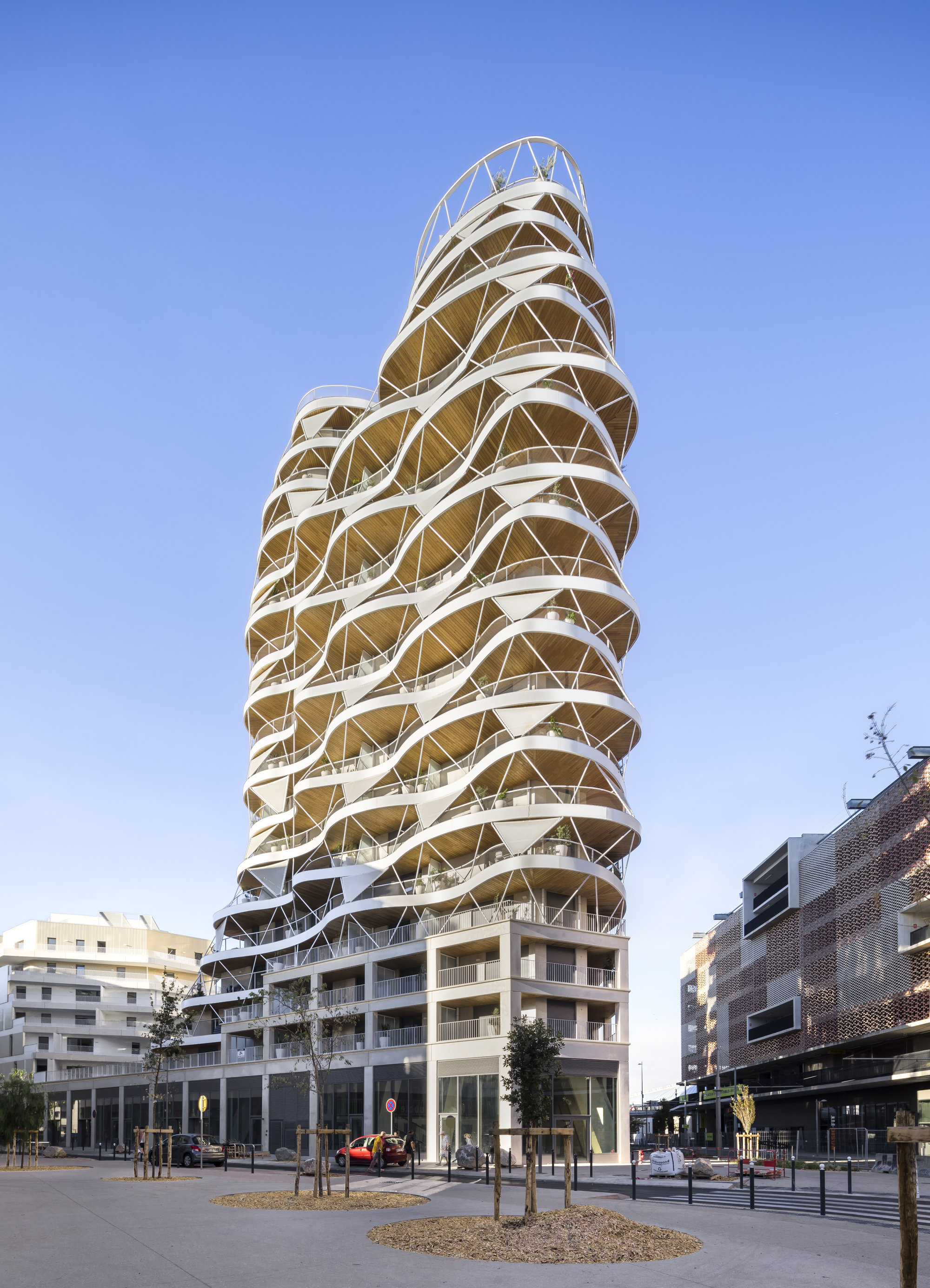 Street view of the tower showing its diagonal structural exoskeleton and stacked terraces under clear sky