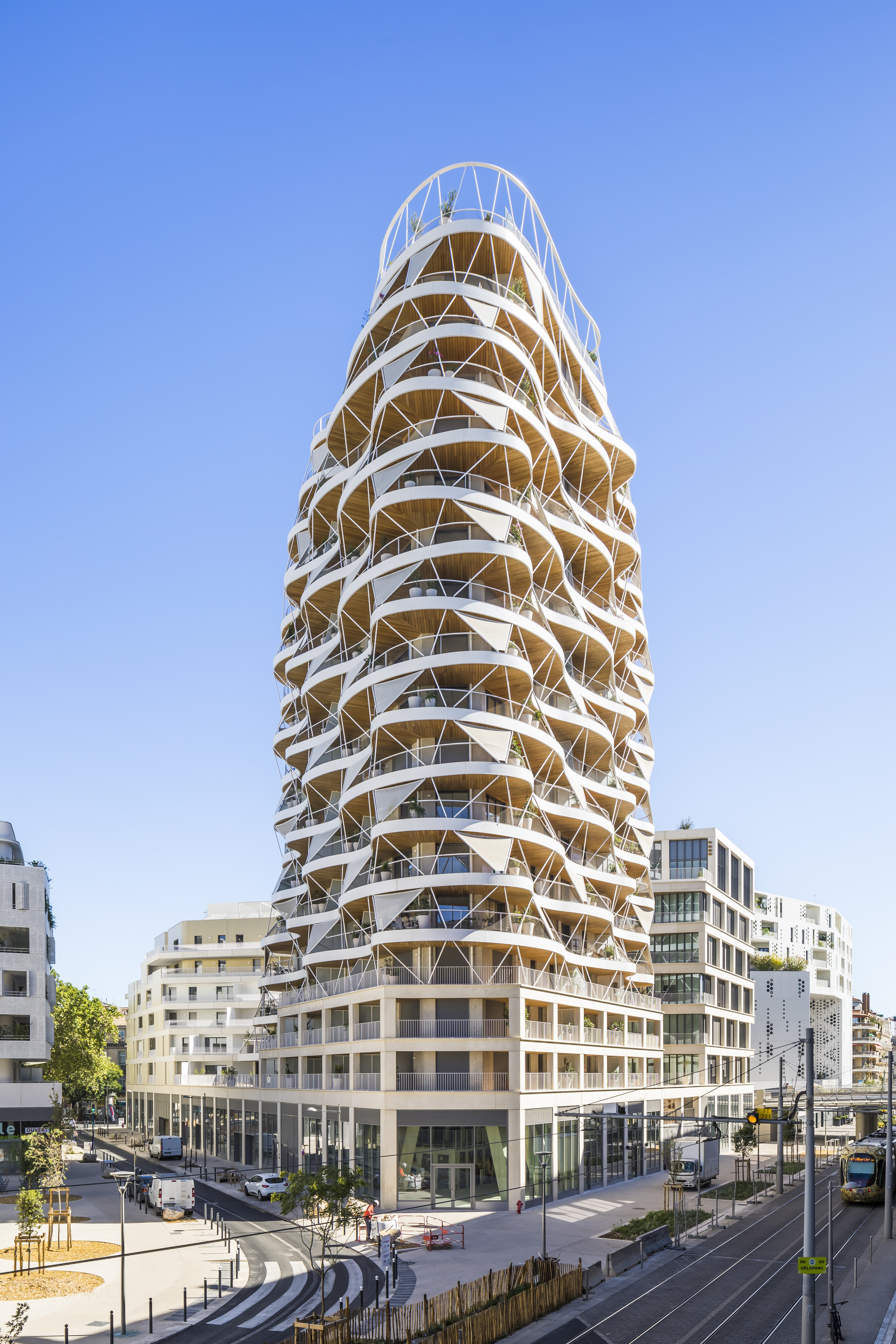 Corner perspective of the spiraling tower with its triangulated facade above a rectangular podium base