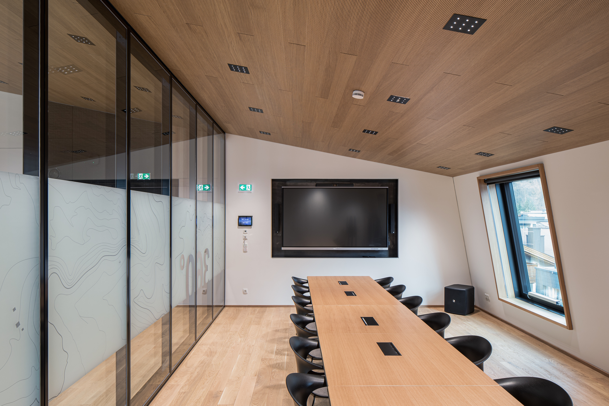 Conference room with timber ceiling, long table with black chairs and a wall-mounted screen