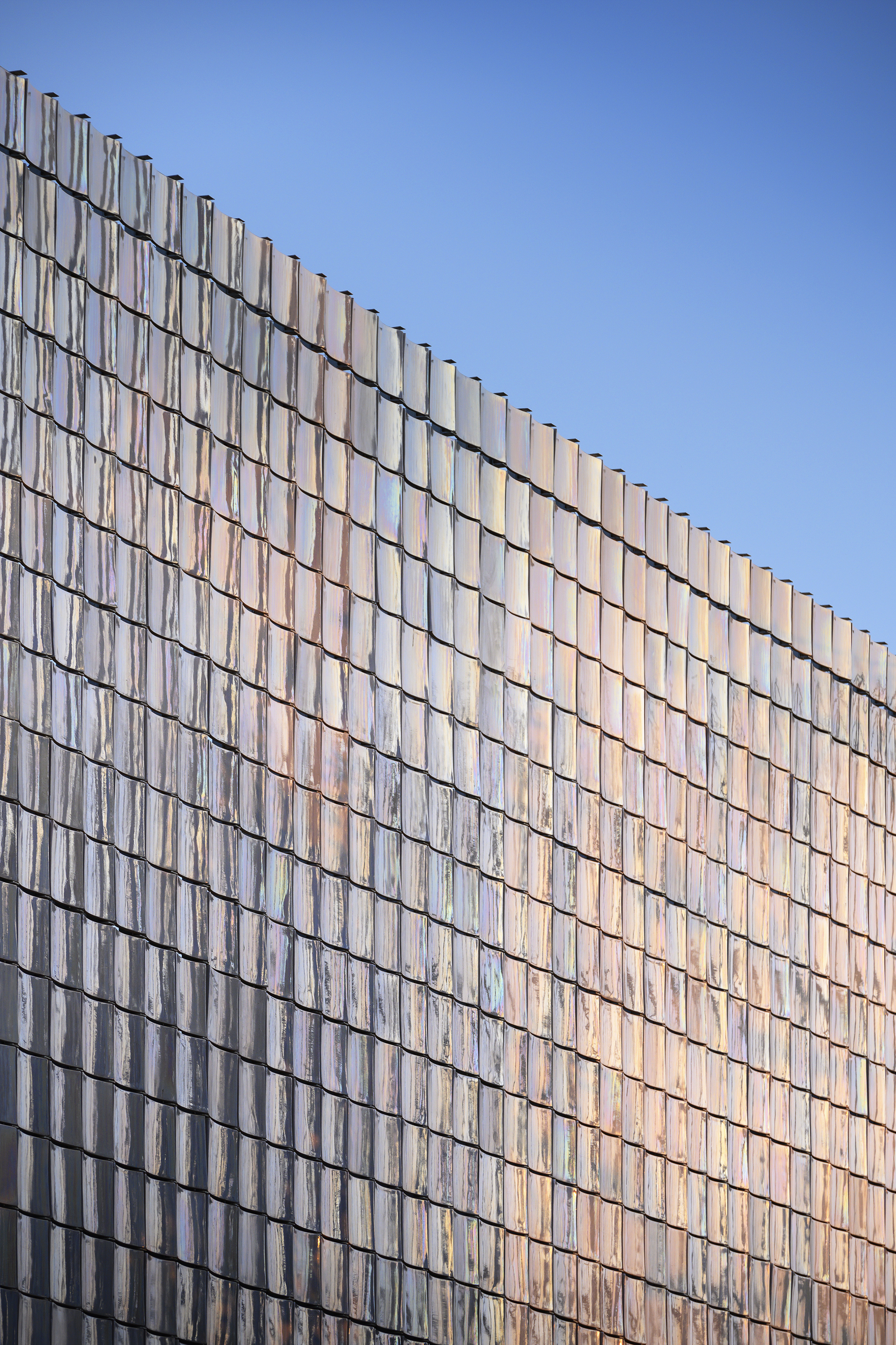 Angled view of the glass tile curtain wall showing diagonal shadow lines in daylight