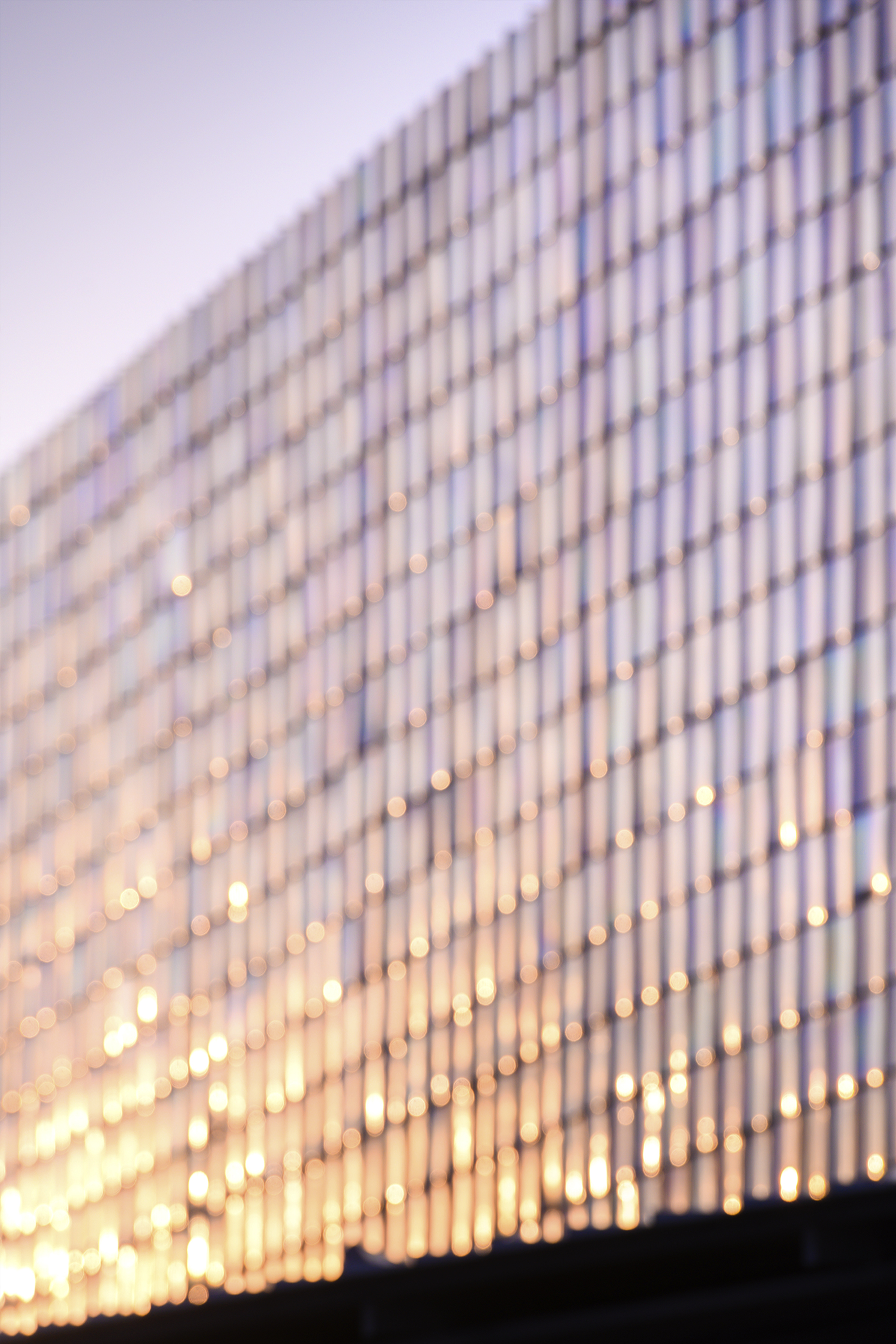 Vertical slat facade with interior lighting glowing through at dusk