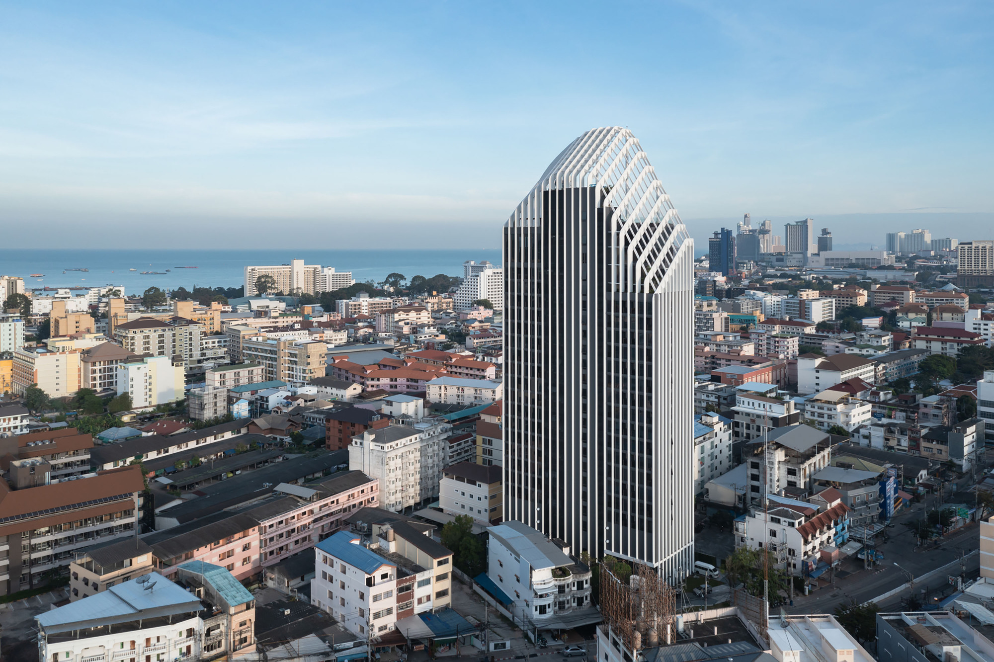 Aerial view of the white vertical fin facade rising above the surrounding residential neighborhood at dusk
