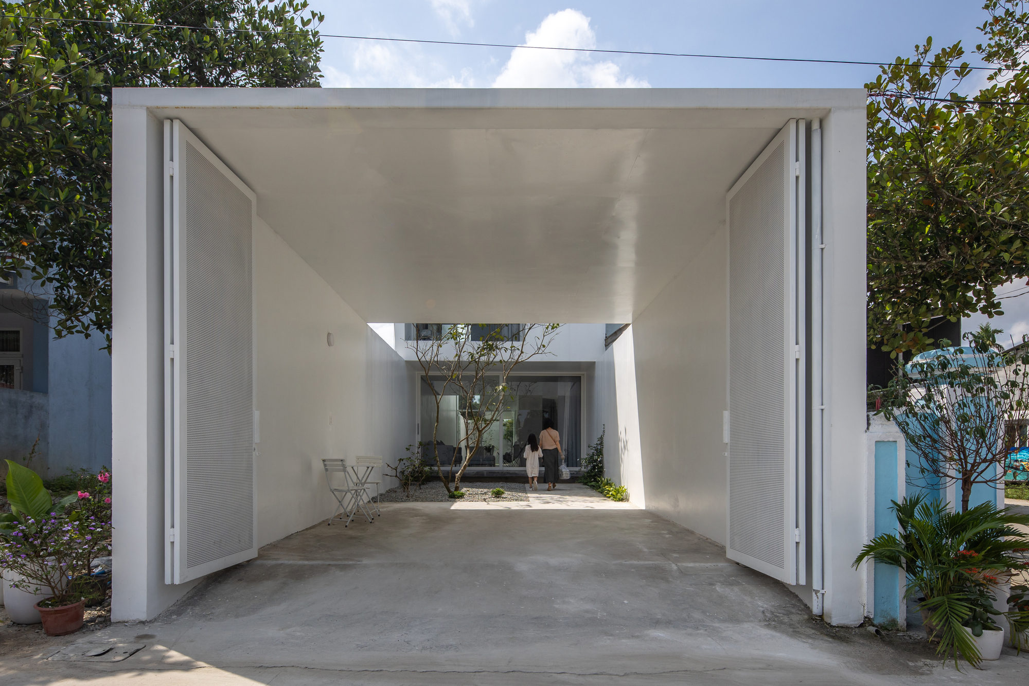 Covered carport with open white doors framing a view through to interior courtyard