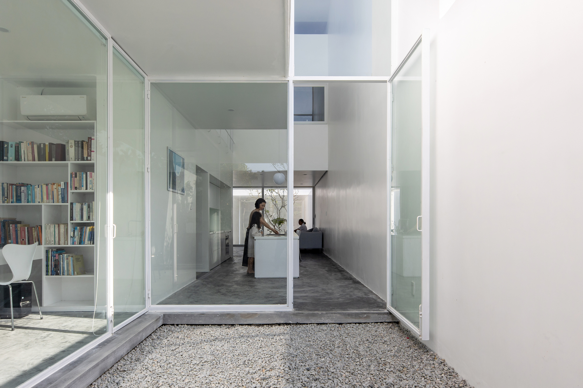 View through open sliding glass doors into the living area with bookshelves and a gravel courtyard