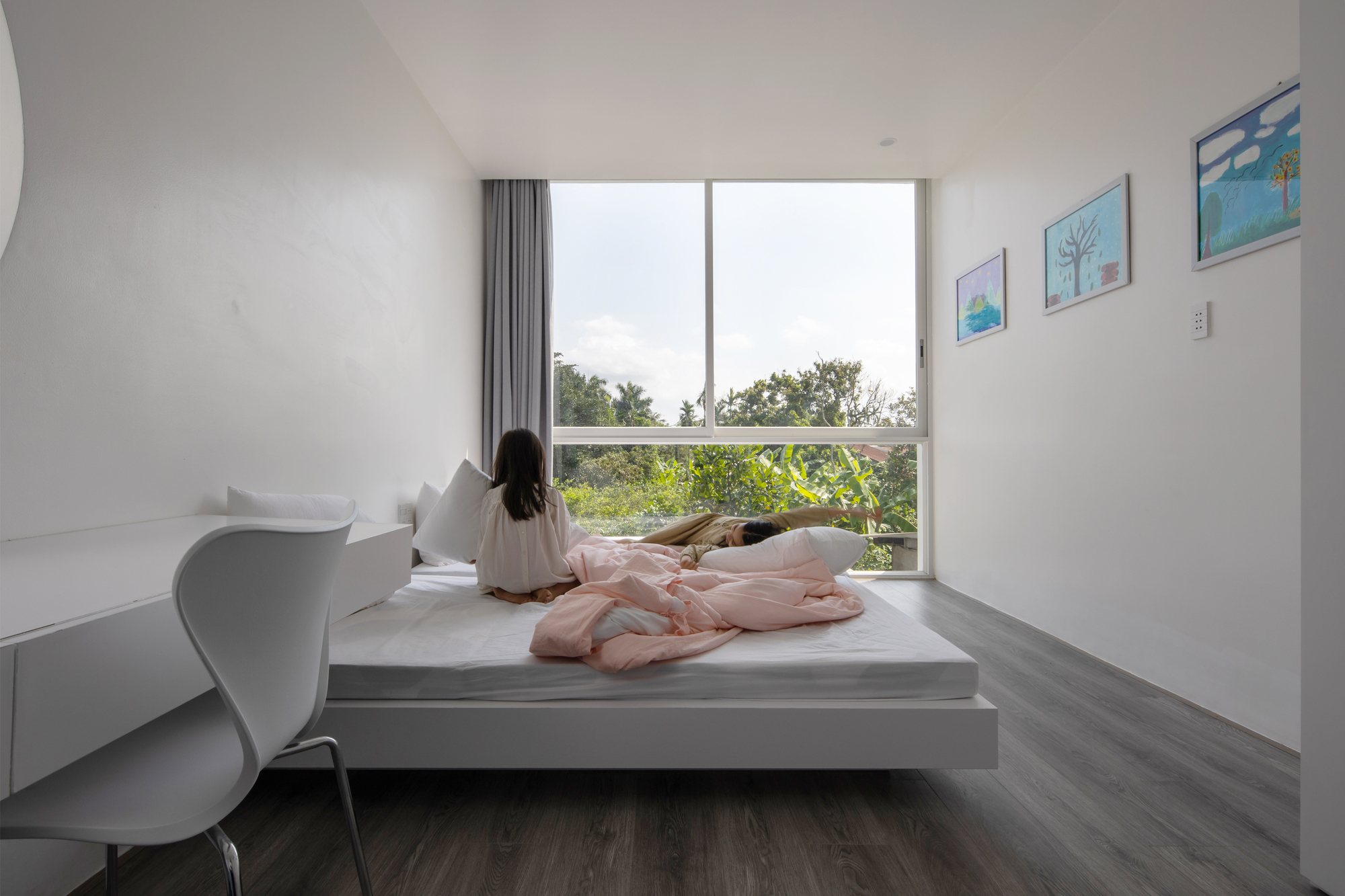 Window seat nook with a seated figure looking out toward trees in daylight