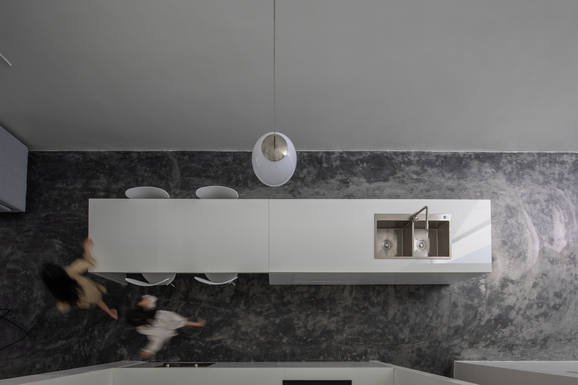 Overhead view of kitchen island with polished stone countertop and two figures passing
