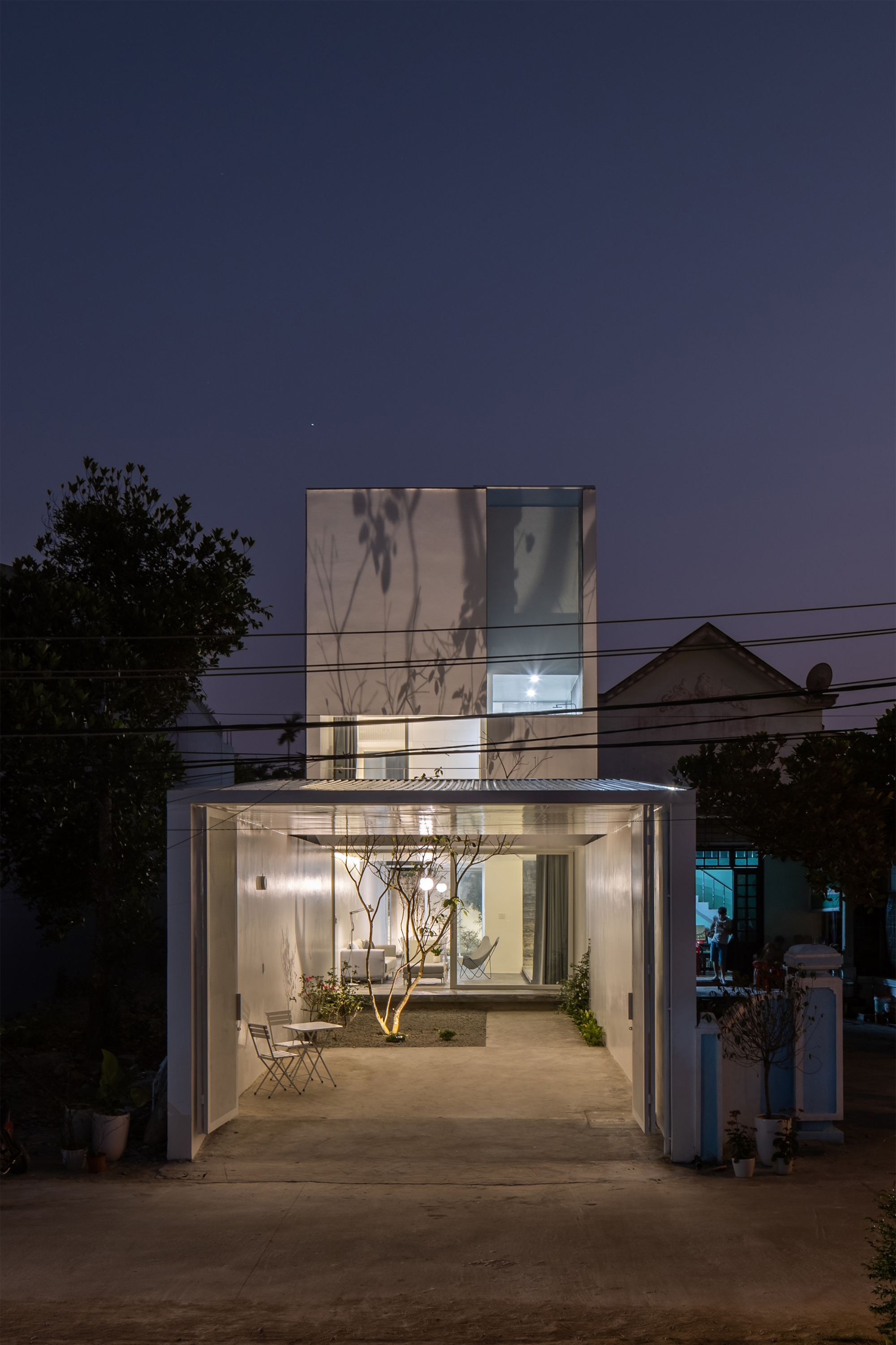Street view of the translucent glass facade and open ground floor at twilight