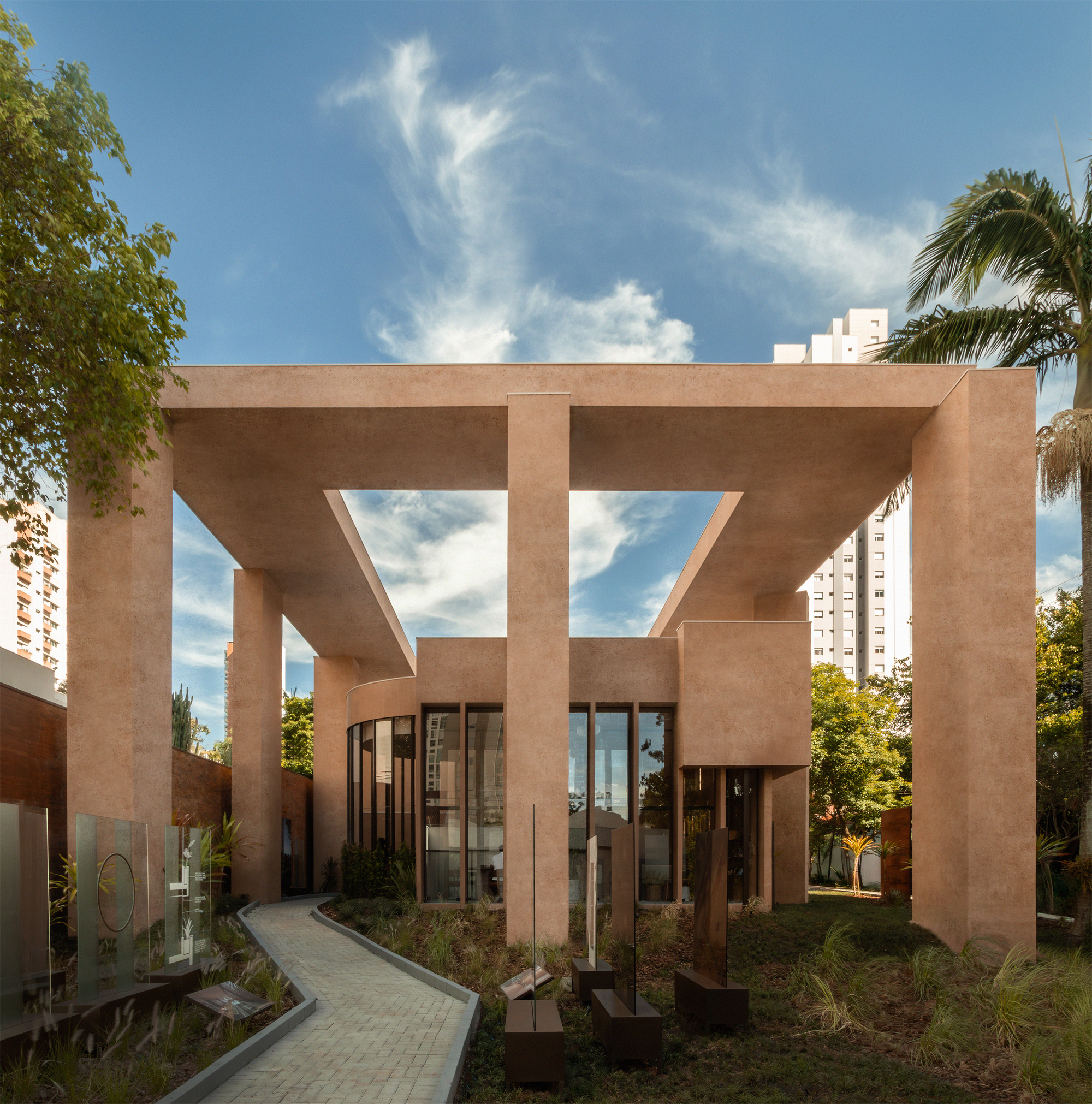 Terracotta stucco facade with angular window voids framing the sky above a landscaped garden pathway