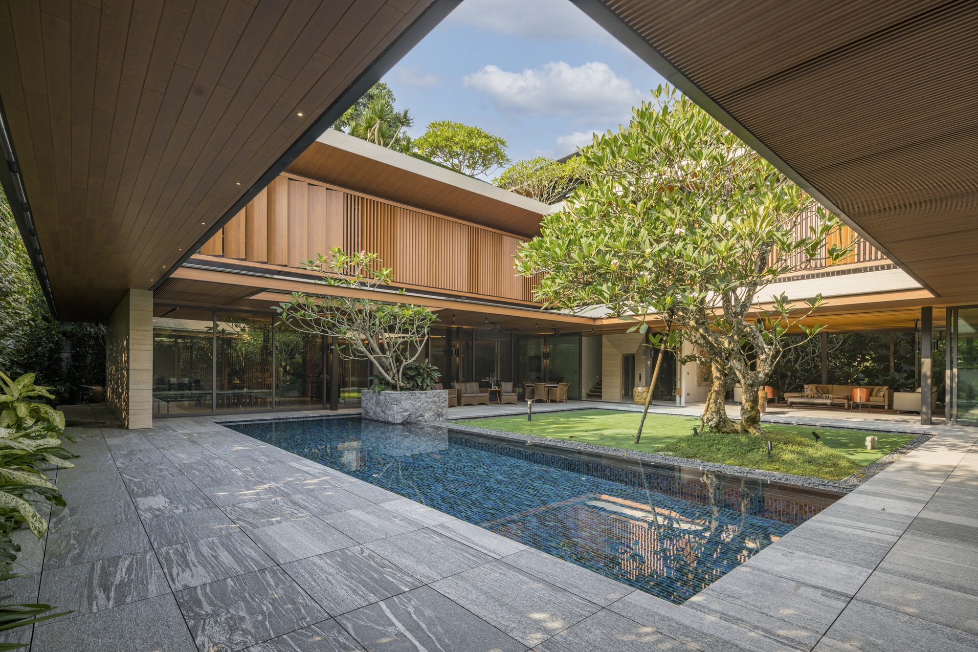 Covered walkway framing the interior courtyard pool and lawn under a slatted timber soffit