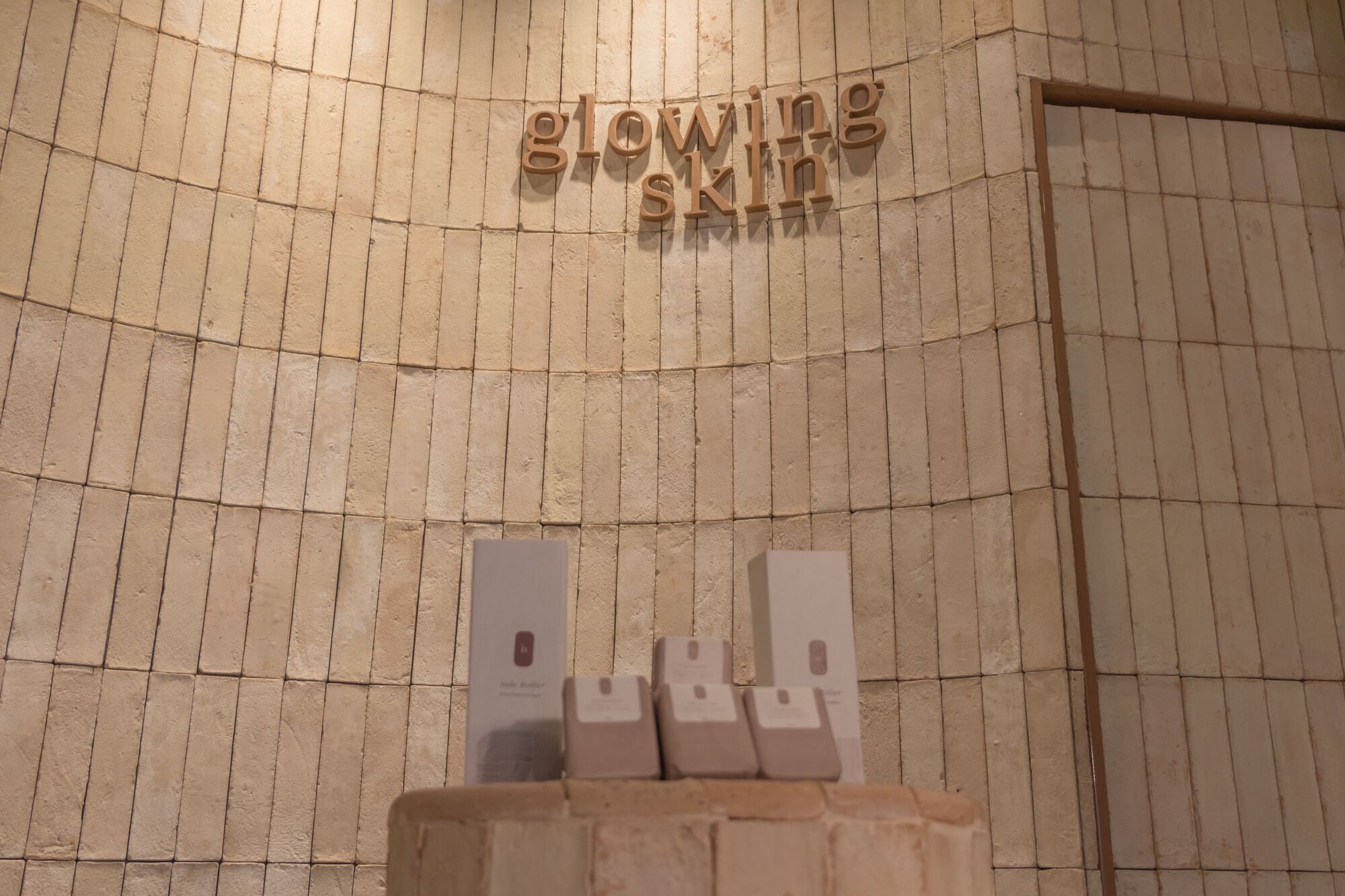 Angled view of curved tiled wall with raised lettering and stepped ledge below