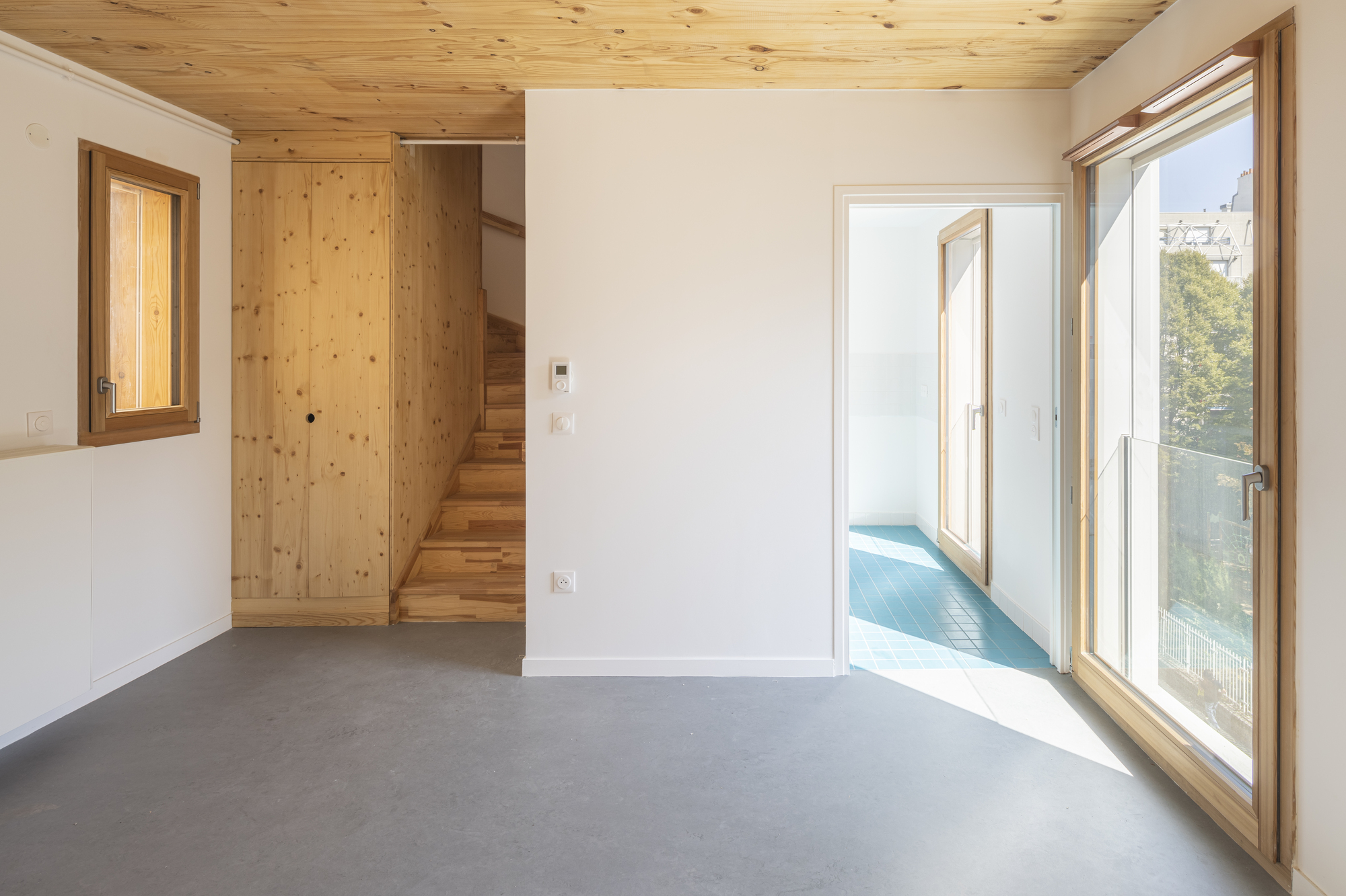Living space with timber-framed glass doors opening to a balcony under morning sunlight