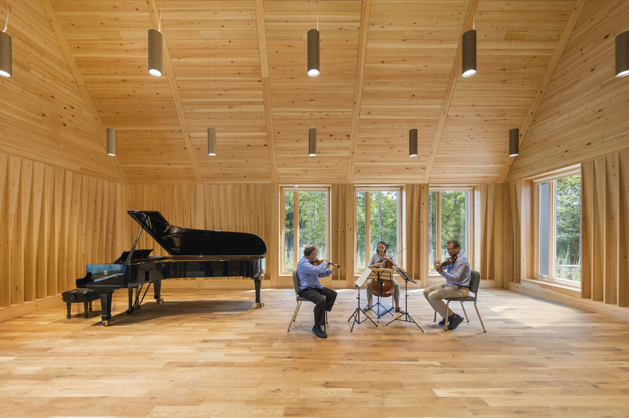Chamber ensemble rehearsing in the wood-clad space with views to the landscape beyond