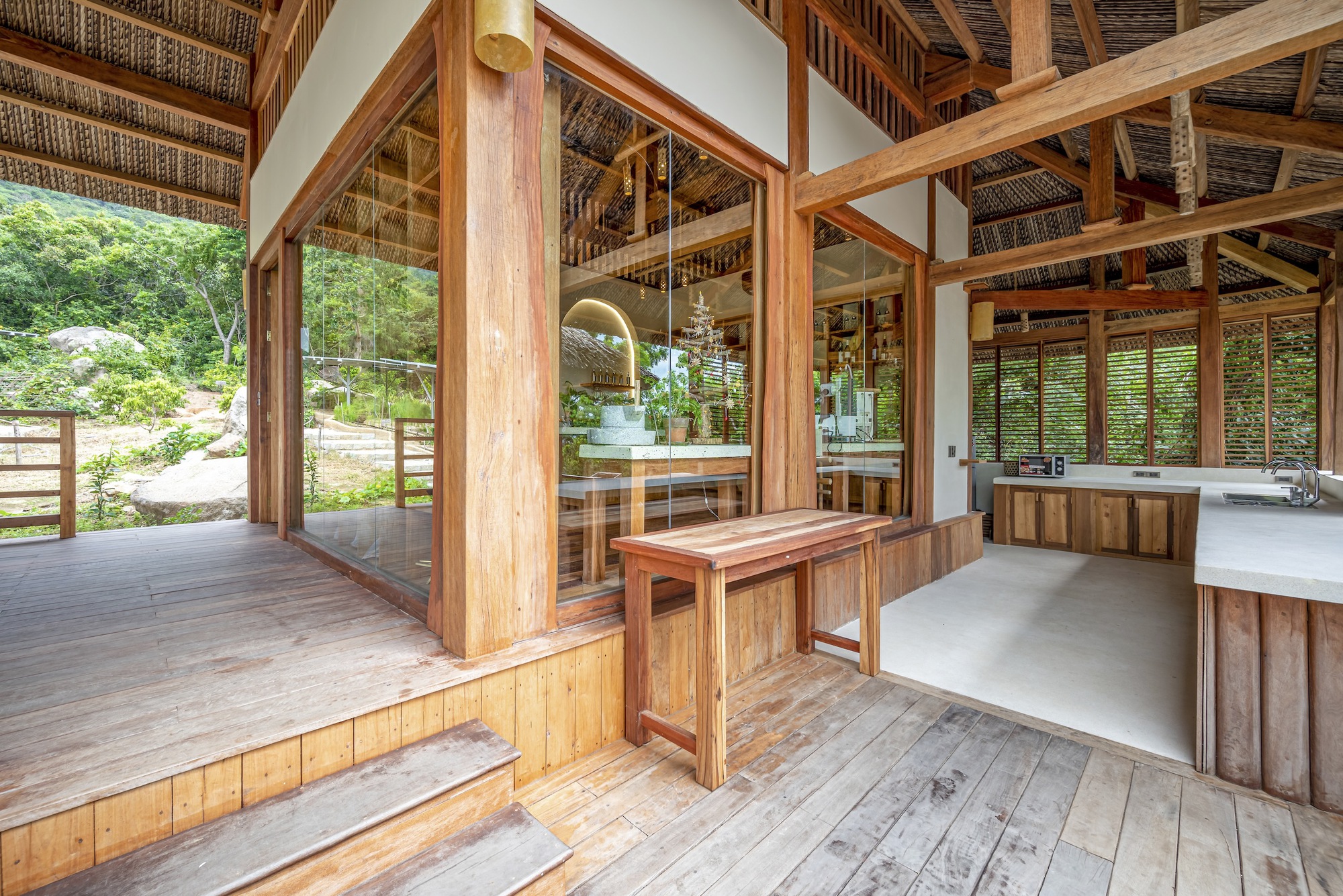 Interior threshold between timber deck and concrete floor with glass partition and louvered screens beyond