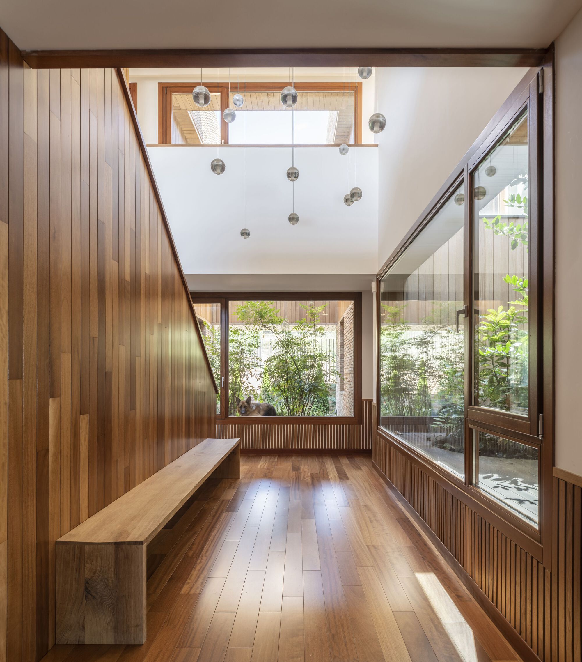 Double-height entryway with vertical timber cladding and glass pendant lights above