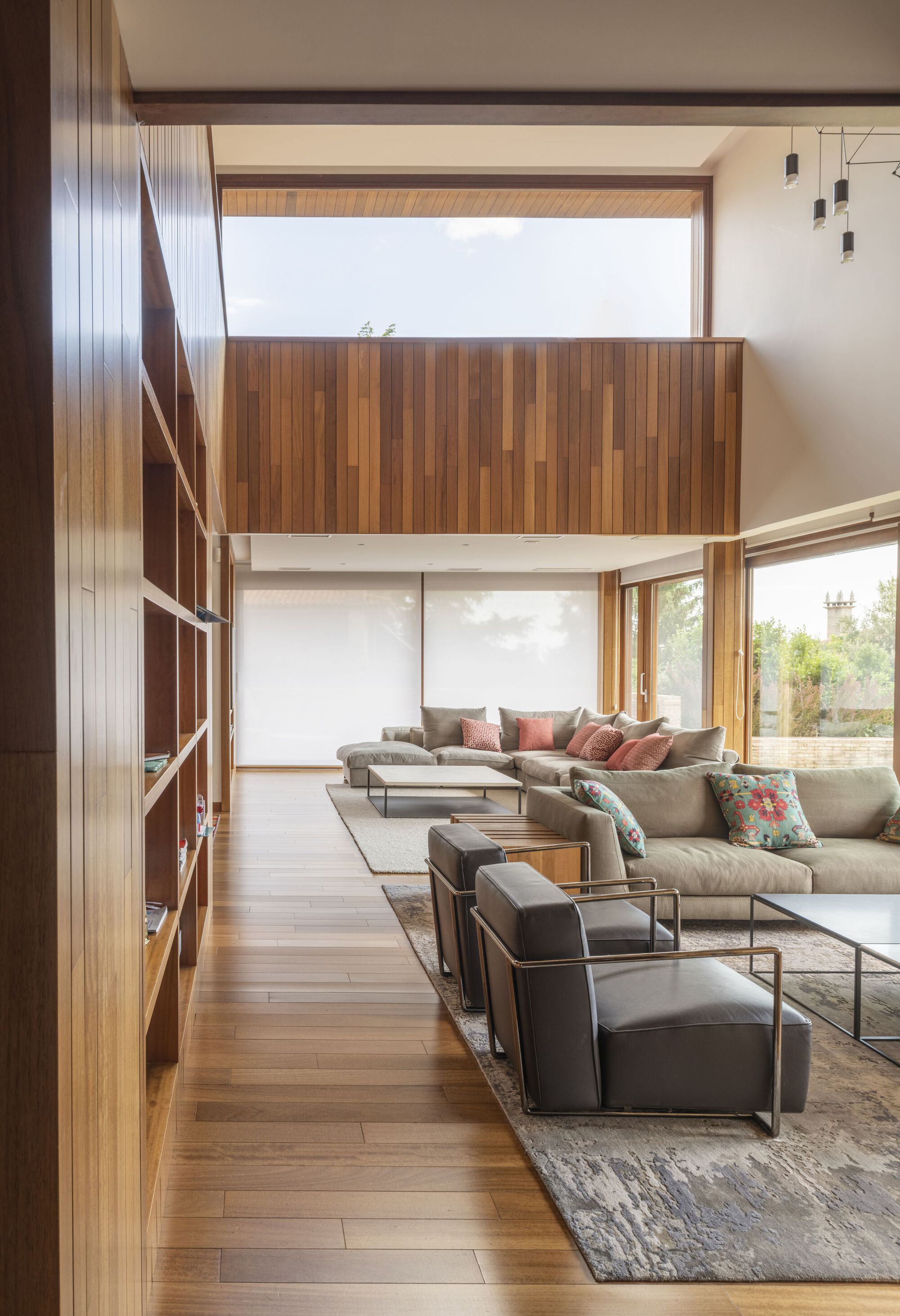 Living room with mezzanine bridge and built-in timber shelving along one wall