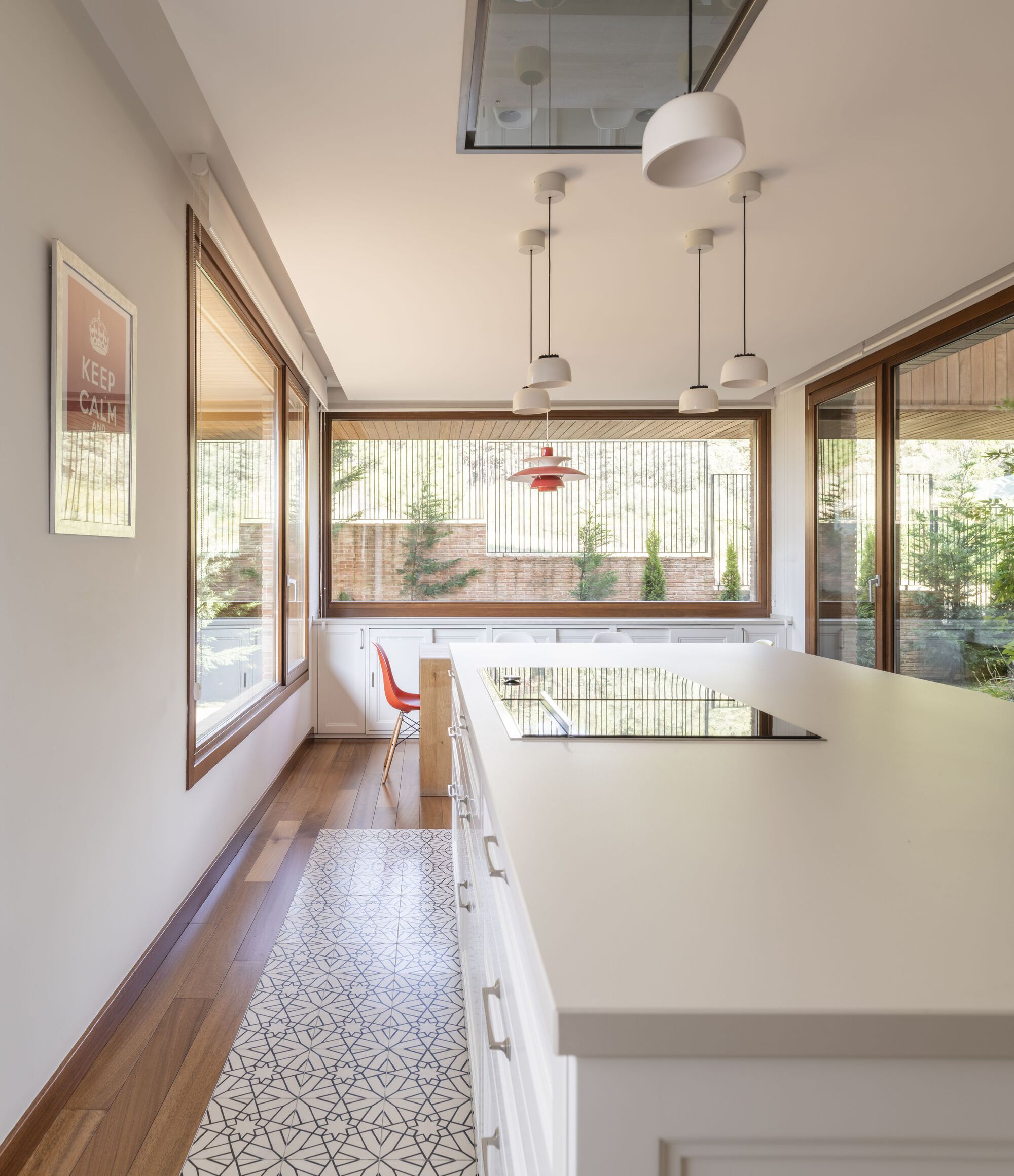 Kitchen with patterned floor tiles and timber-framed windows overlooking a planted courtyard
